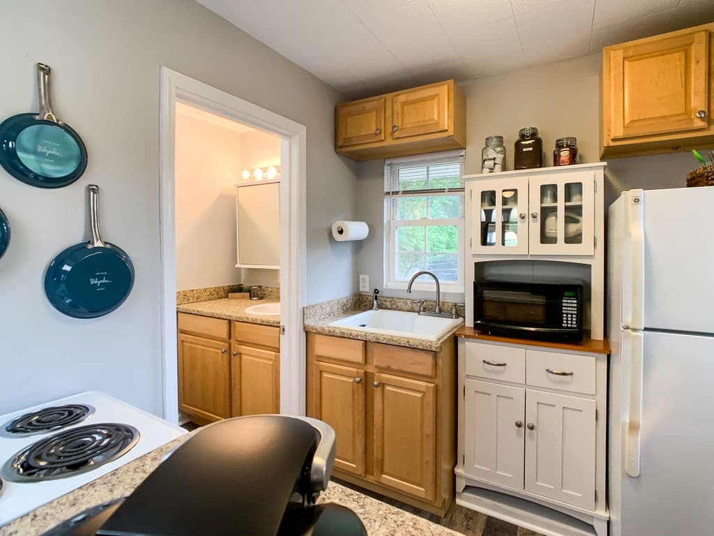 A tiny kitchen with a 4 burner stove and oven, microwave, and full sized fridge at the Hound Haus.