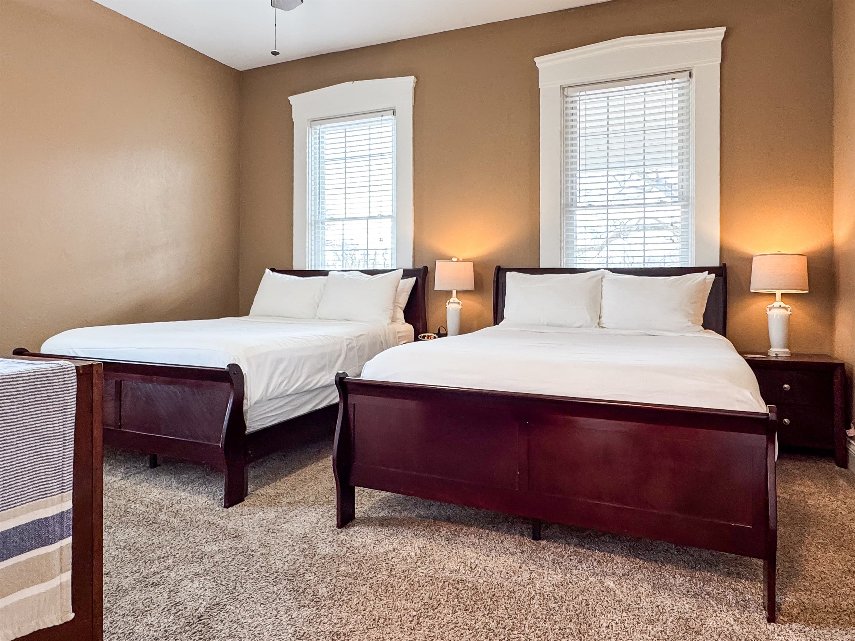 Spacious main level bedroom includes two plush queen size beds with crisp white linens and a full bathroom with combo tub and shower off the hallway at Aussie Cottage.