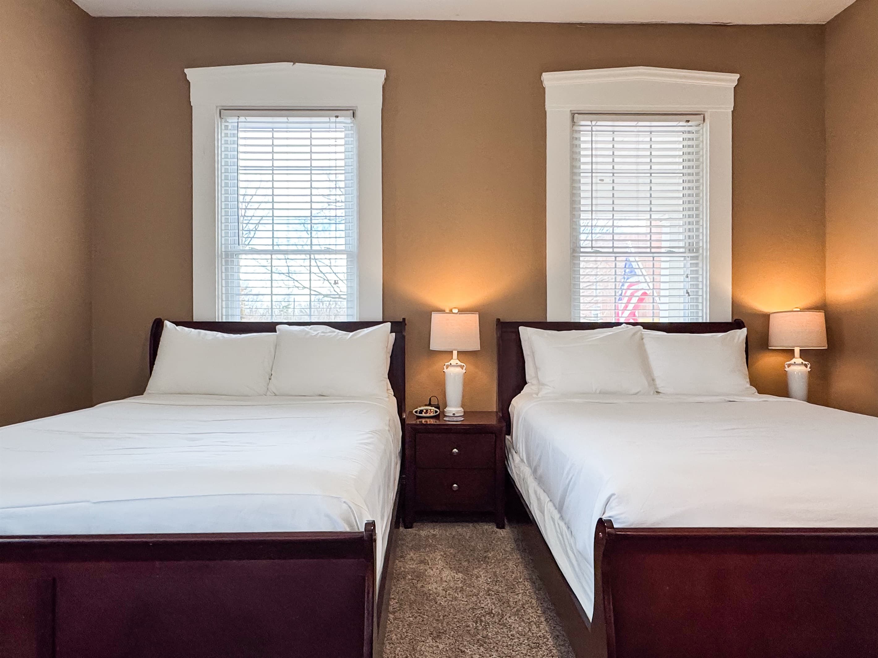 Spacious main level bedroom includes two plush queen size beds with crisp white linens and a full bathroom with combo tub and shower off the hallway at Aussie Cottage.