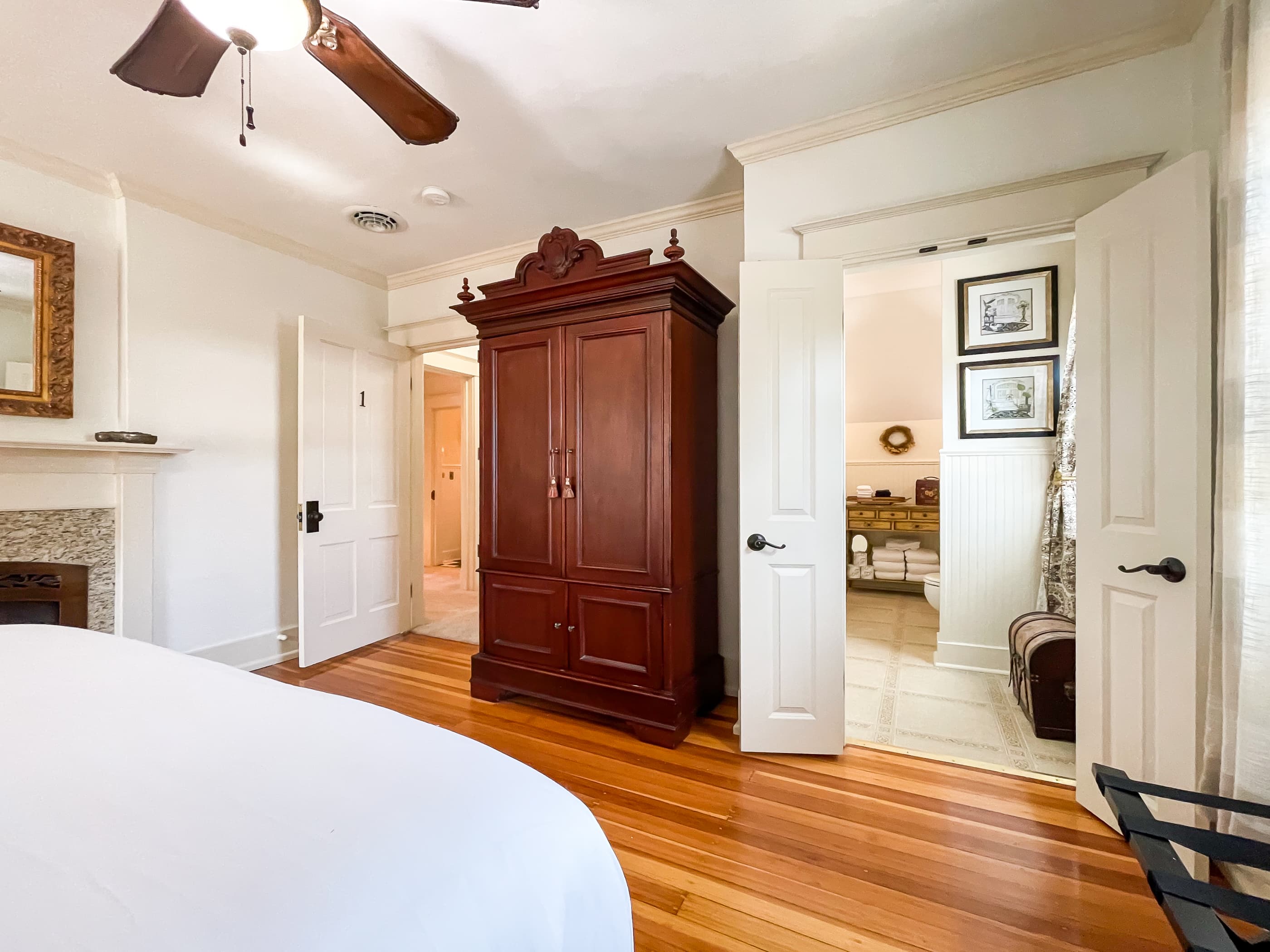 Spacious and airy primary queen bedroom with crisp white linens, flat screen Smart TV in the wardrobe, a nonworking fireplace and an en suite bathroom with walk-in shower at The Beekeeper's Cottage.