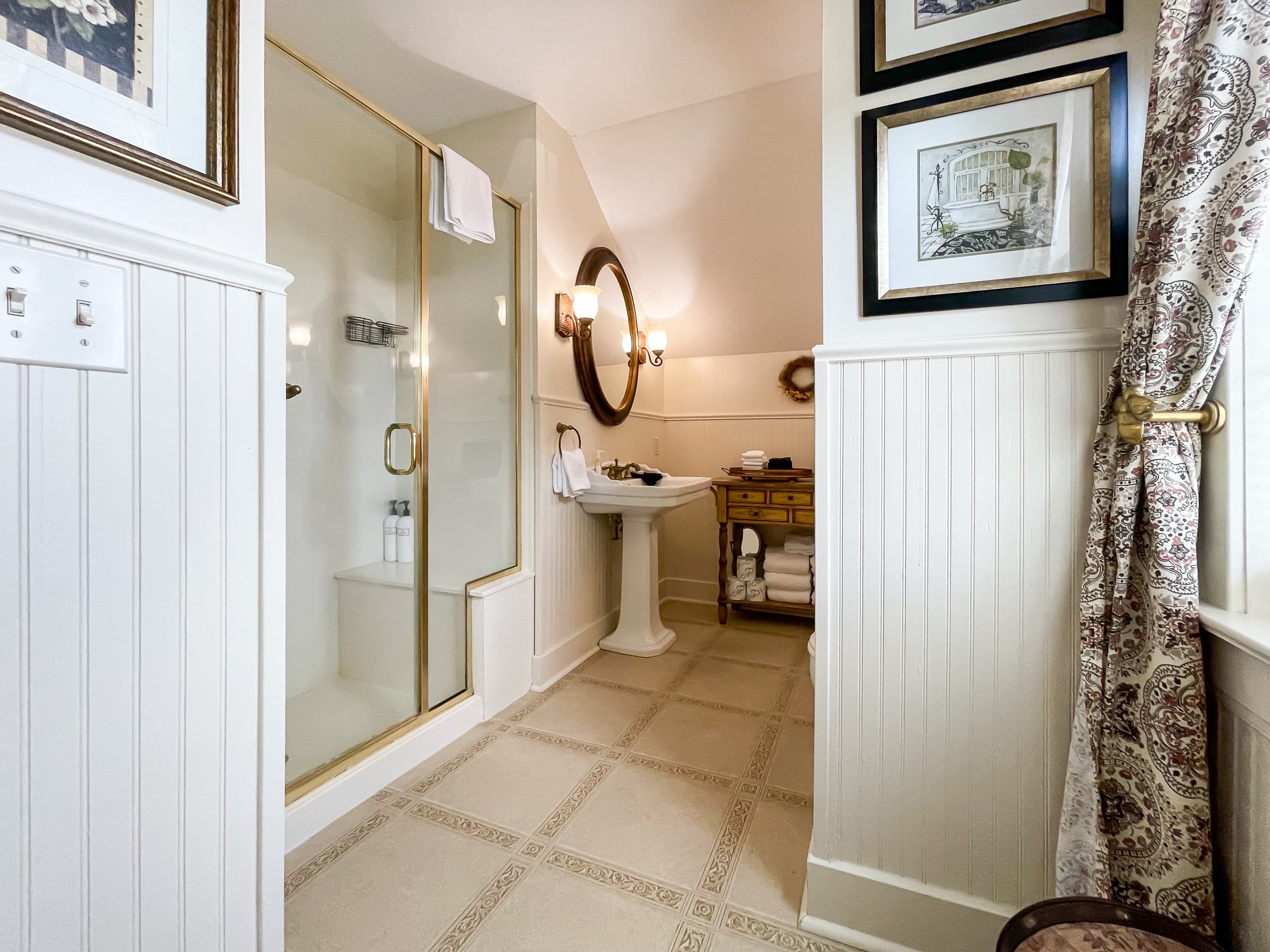 An en suite bathroom with walk-in shower, double pedestal sinks and walk-in shower off the primary bedroom at The Beekeeper's Cottage.
