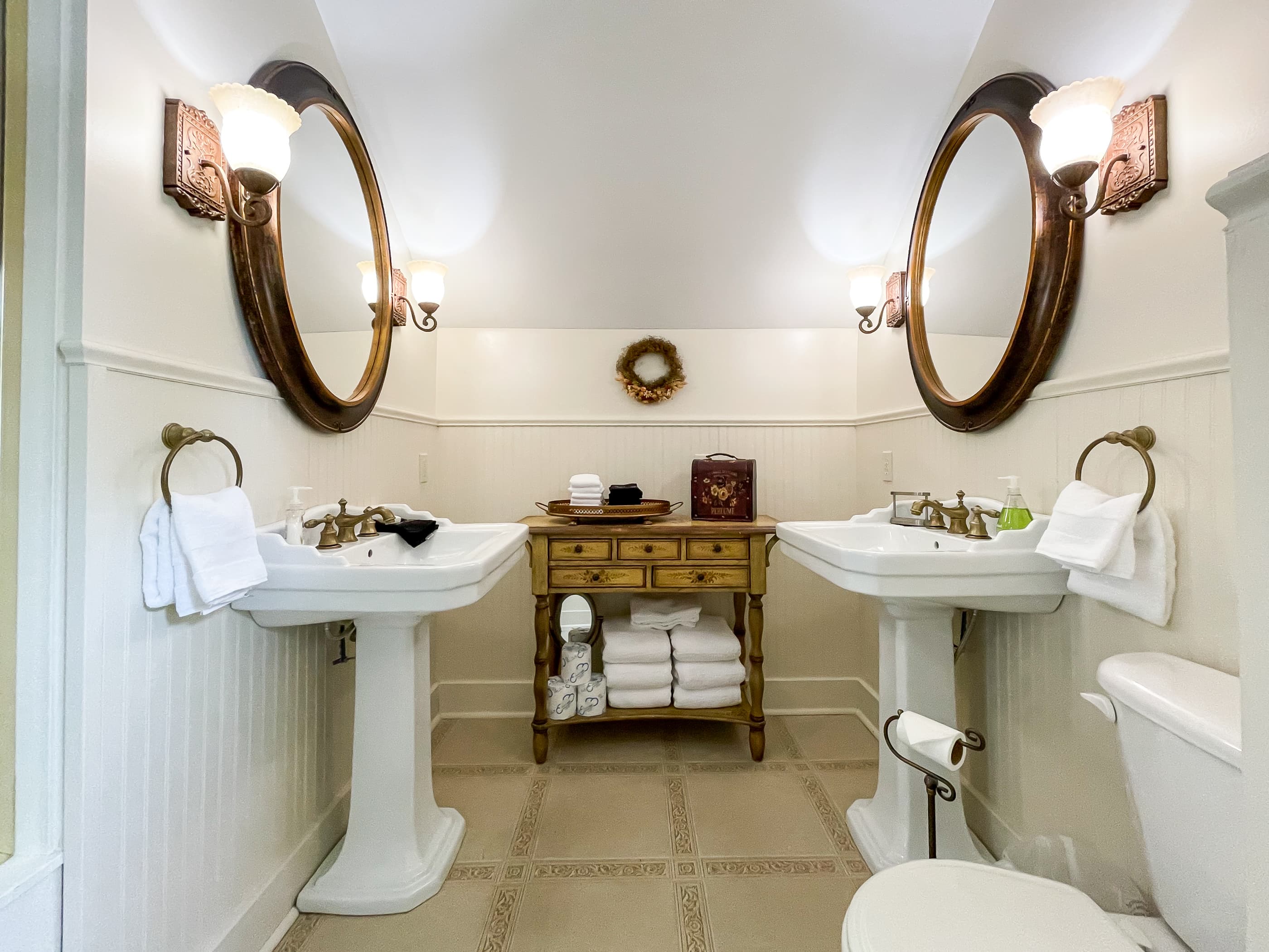 An en suite bathroom with double pedestal sinks and walk-in shower off the primary bedroom at The Beekeeper's Cottage.