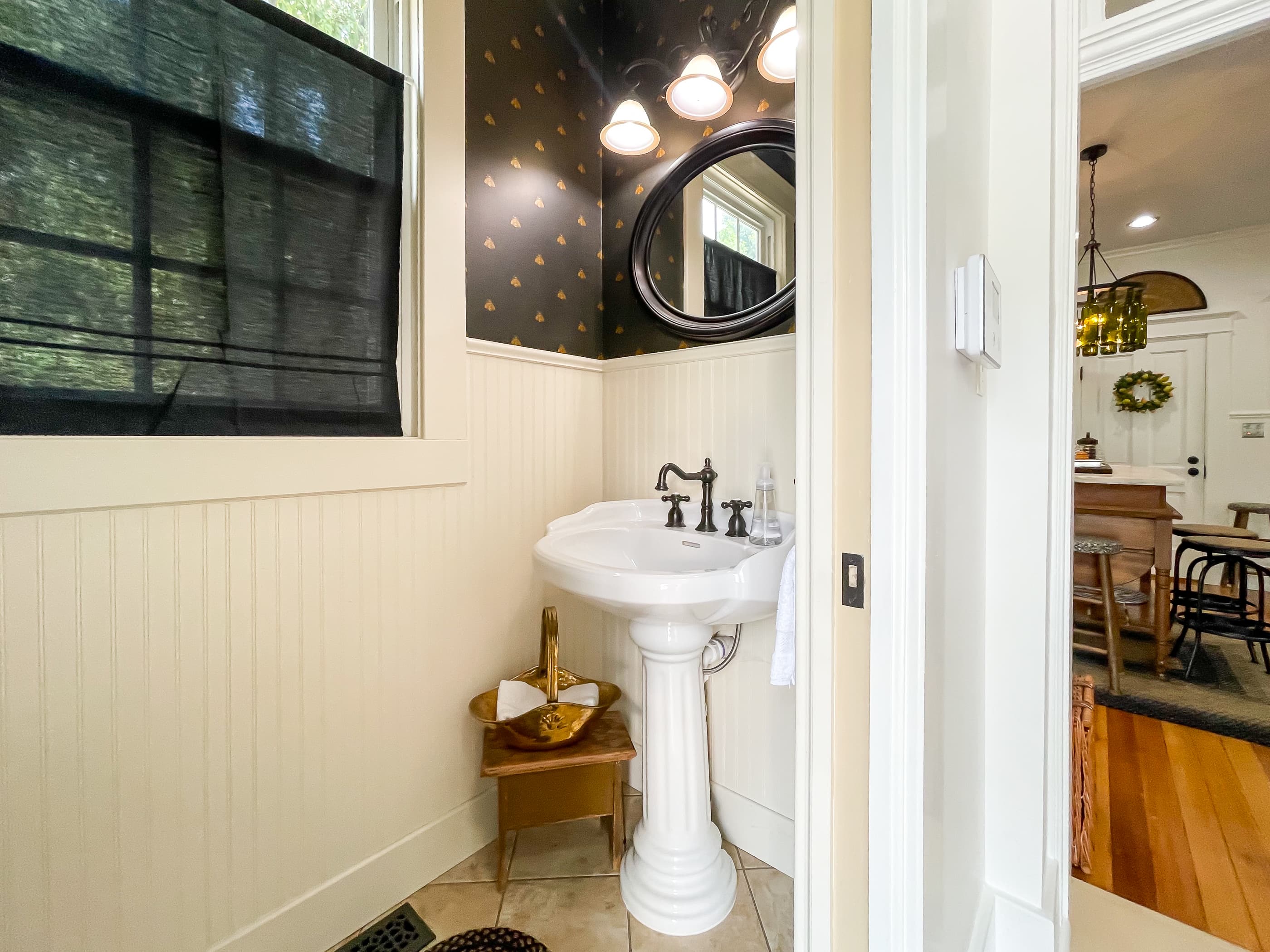 A half bath with pedestal sink is located off the kitchen by the back door with the bee theme decor at The Beekeeper's Cottage.