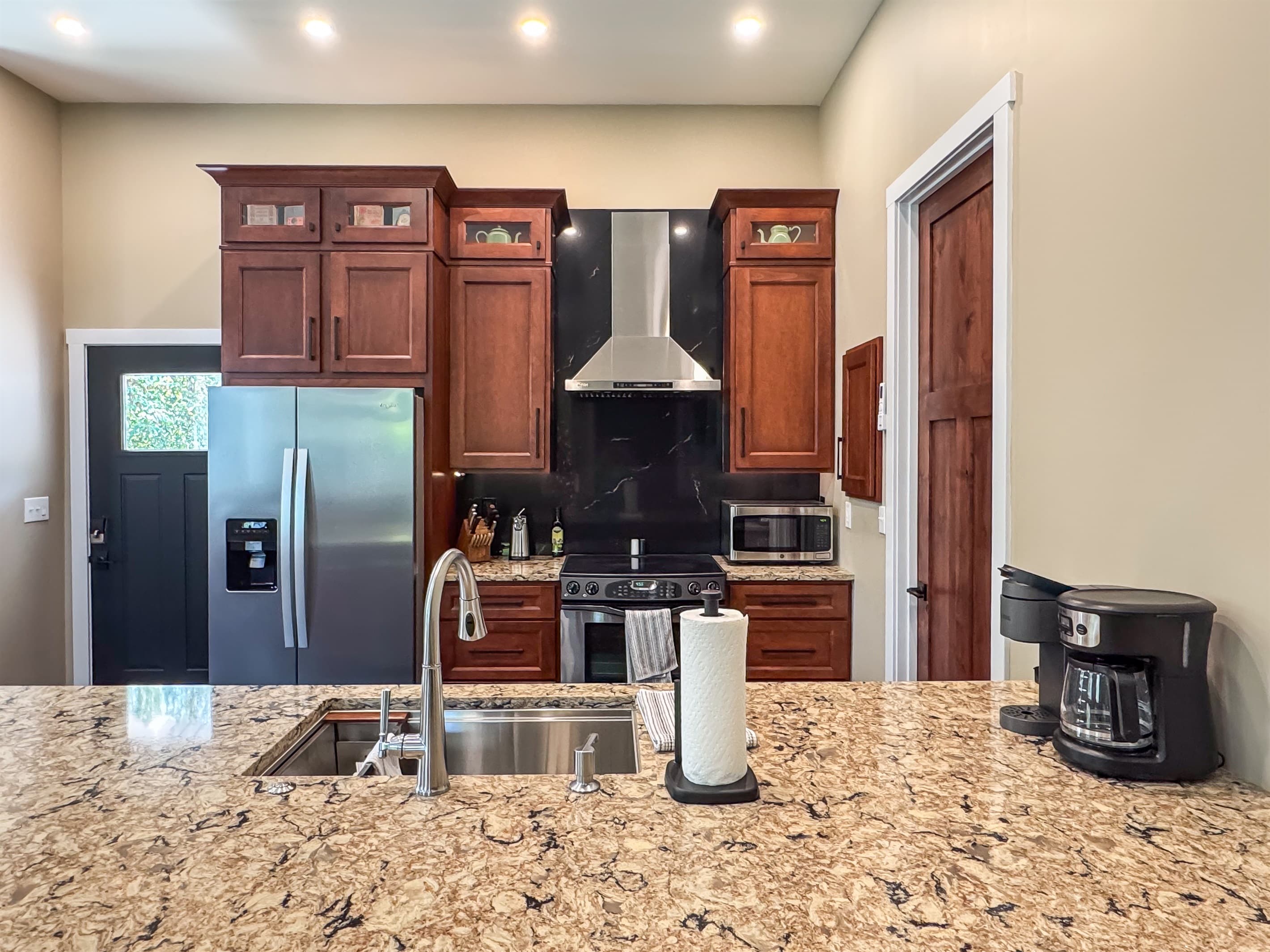 Full kitchen with ample counter space, kitchen tools, small appliances, and main entry door.