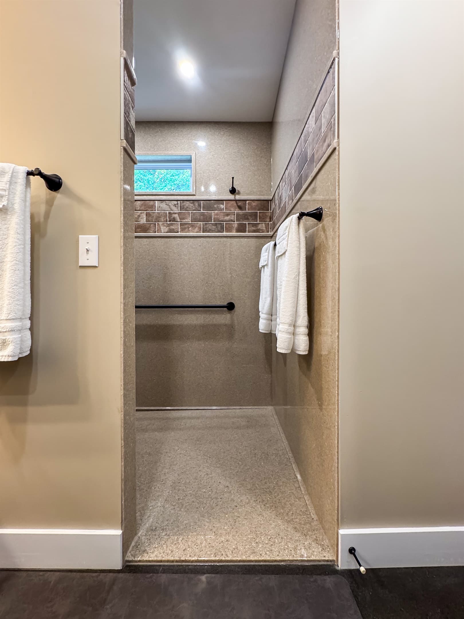 Oversized stand up shower with large bench, grab bars, and handheld shower head.