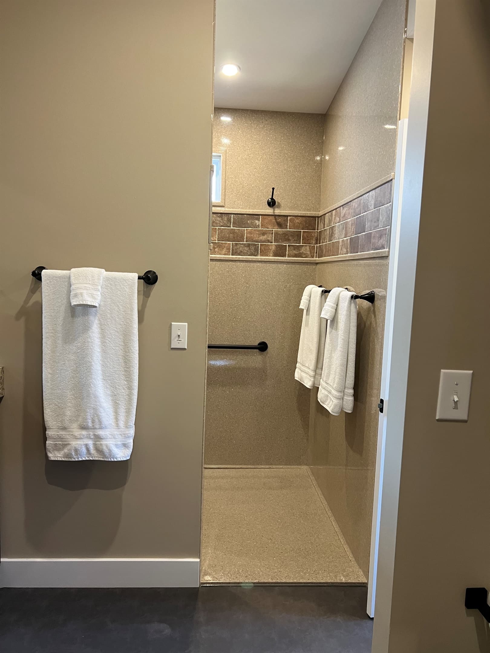 Oversized stand up shower with large bench, grab bars, and handheld shower head.
