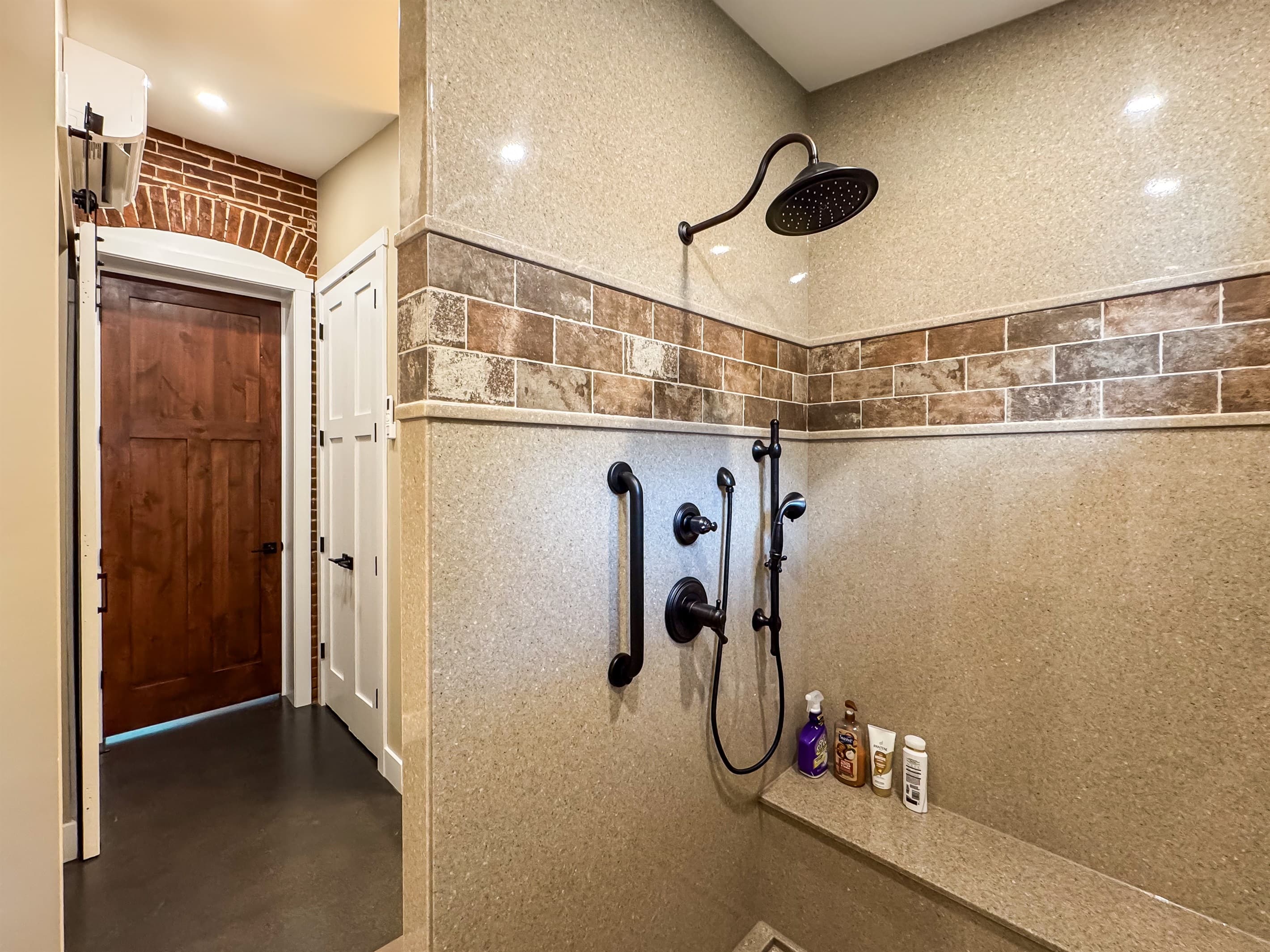 Oversized stand up shower with large bench, grab bars, and handheld shower head.