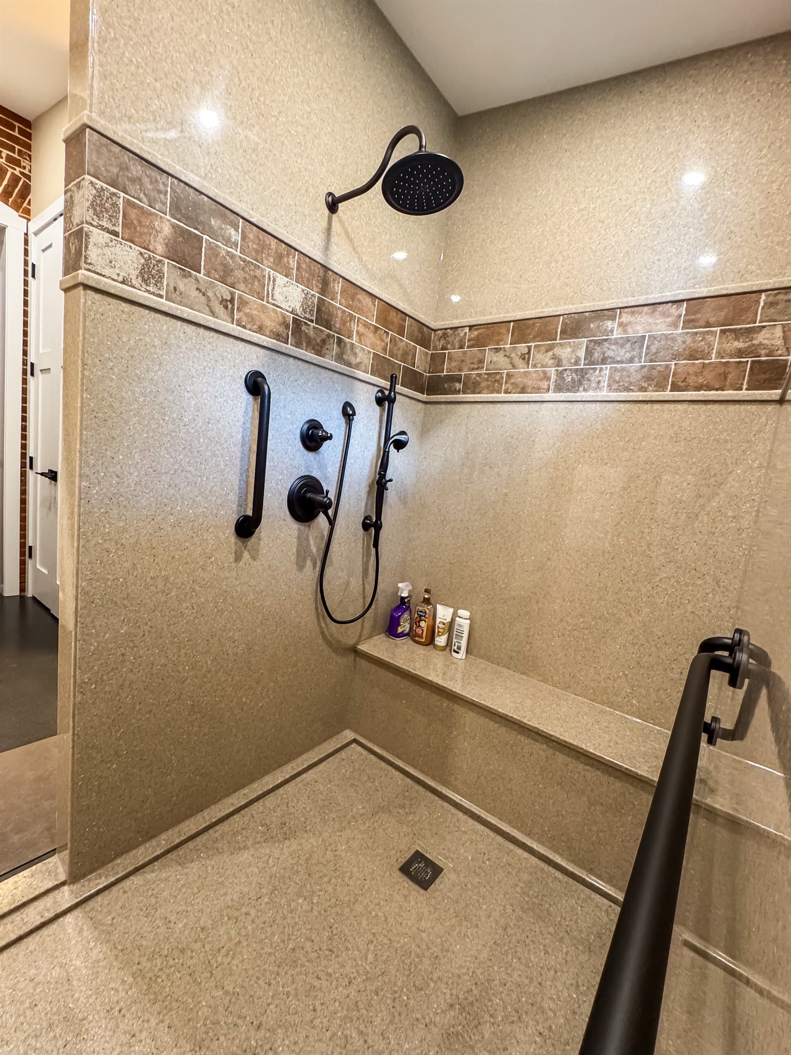 Oversized stand up shower with large bench, grab bars, and handheld shower head.