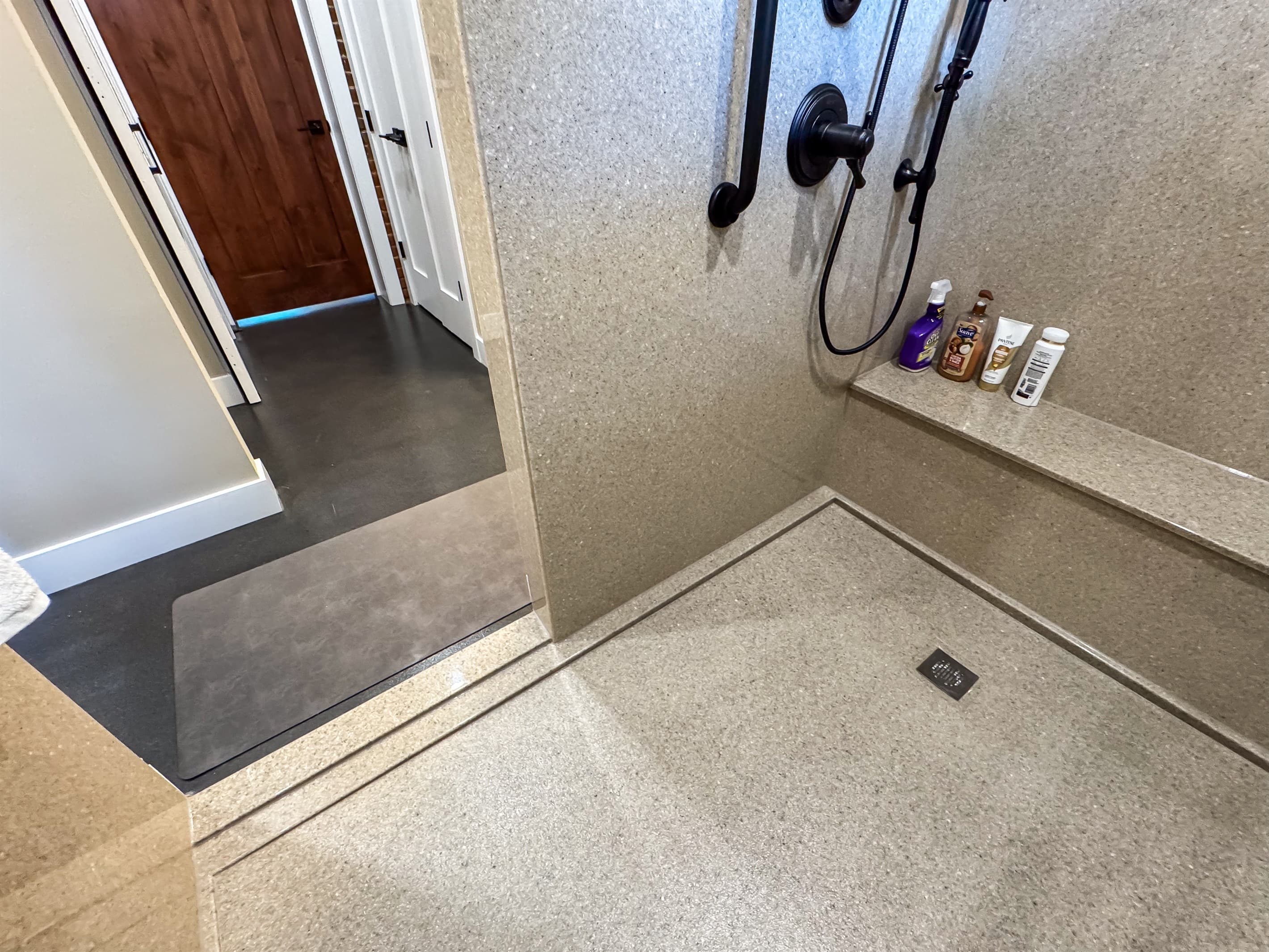 Oversized stand up shower with large bench, grab bars, and handheld shower head.
