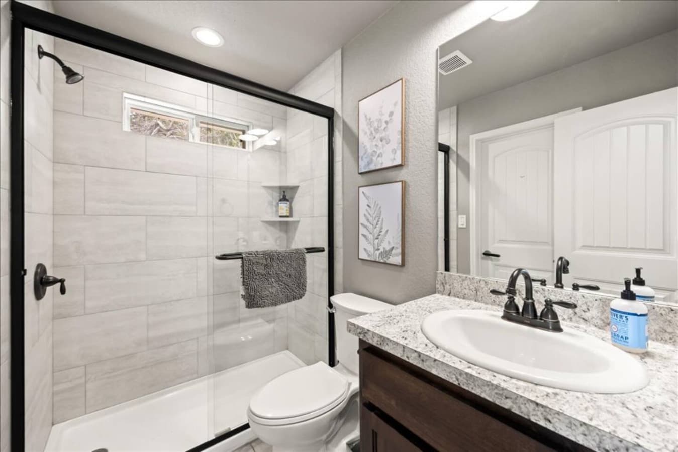 "This sleek and modern bathroom features a spacious glass walk-in shower, granite countertops, and thoughtfully stocked essentials. A clean and calming space to refresh and recharge during your stay."