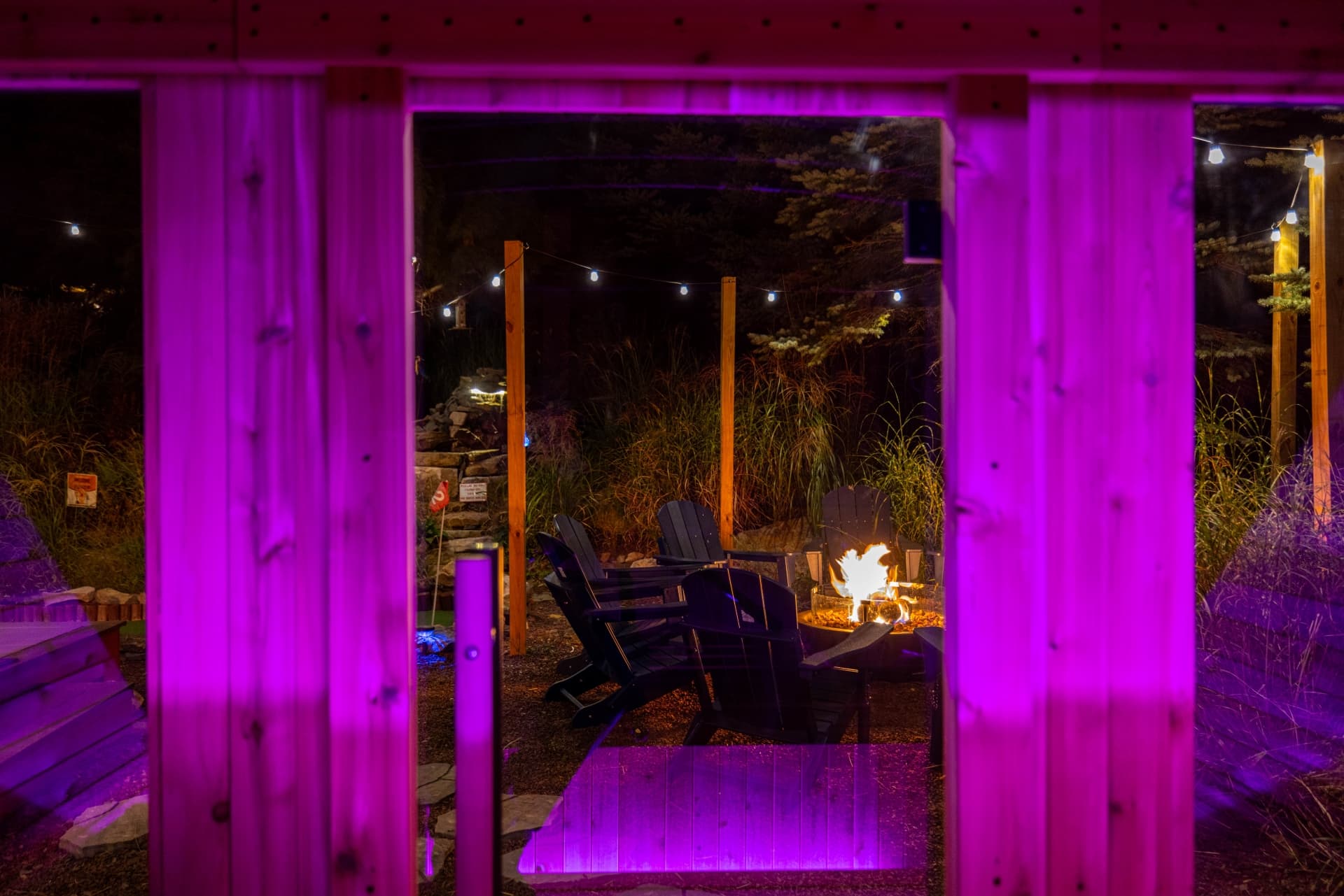View from the sauna 🔥 Step inside our 6-person cube sauna with glowing lights and enjoy the firepit vibes just outside the window. Relax, recharge & soak in the night magic.