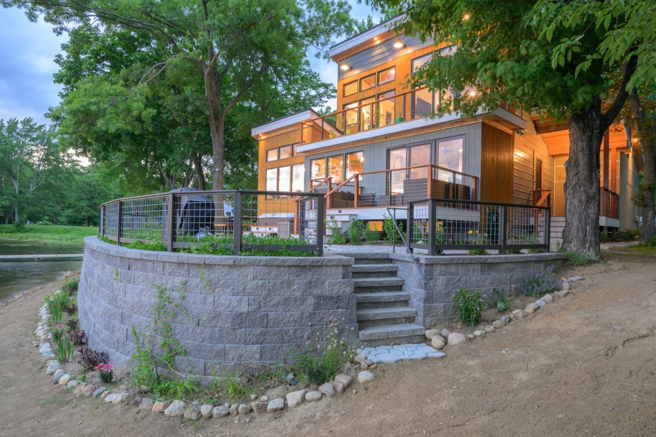 There’s an instant exhale here—the soft evening light, glowing windows, and peaceful waterfront setting create that unforgettable “we’ve arrived” feeling from the moment you walk up.