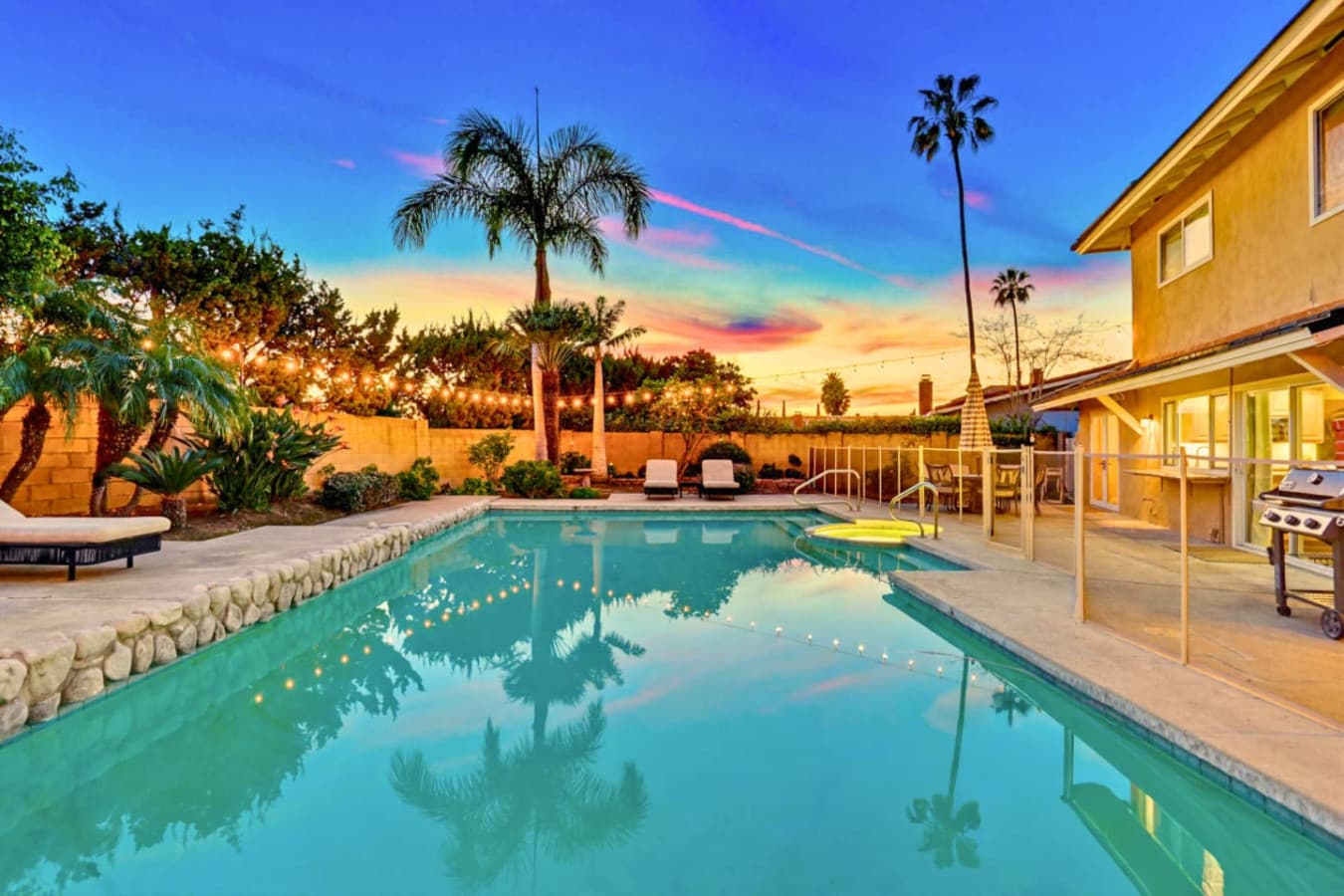 Sparkling backyard pool at sunset w/ lounge seating & palm-lined ambiance for relaxing evenings outdoors
