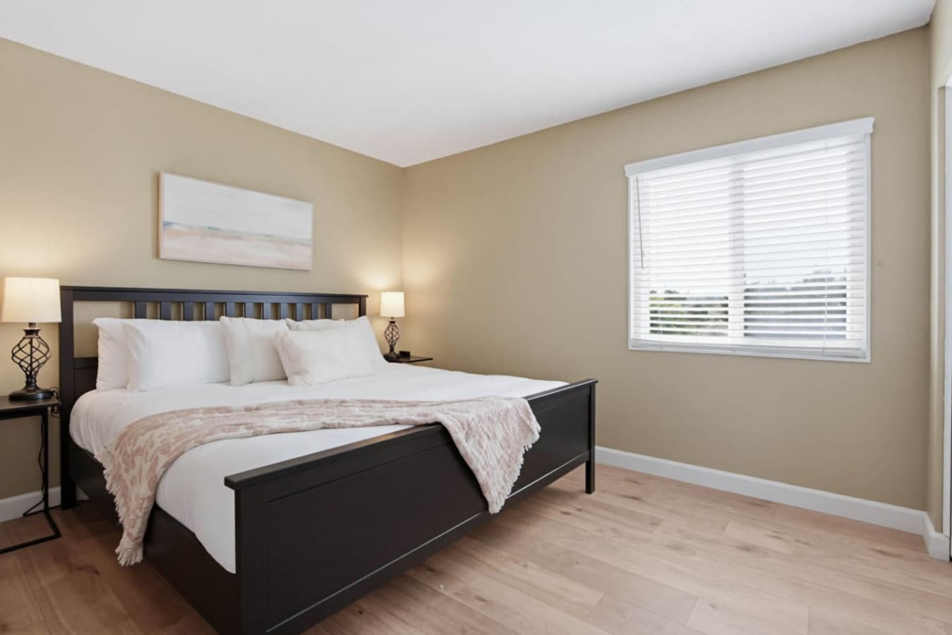 Warm bedroom w/ bed, neutral tones & window light creating a calm retreat