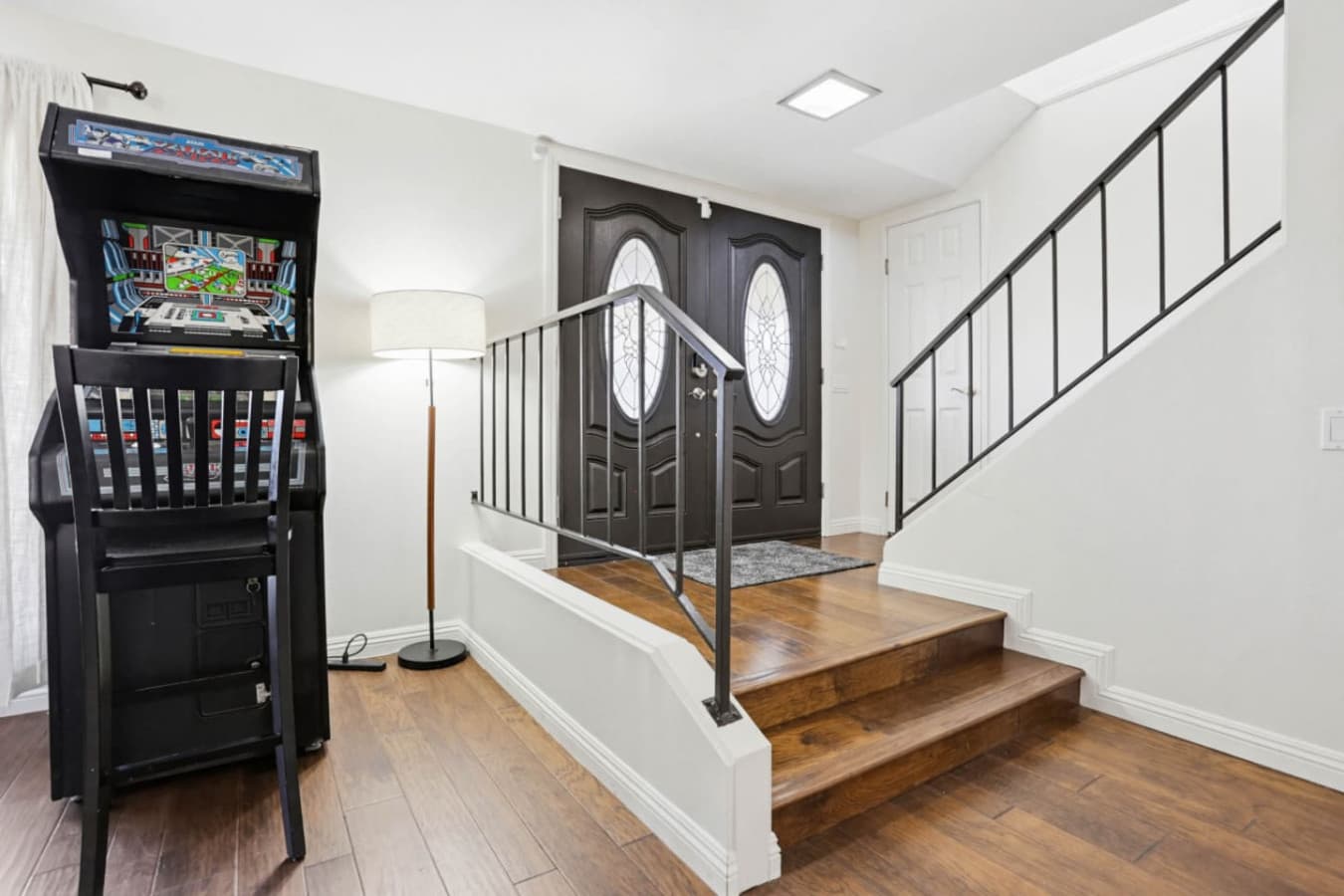 Entry area w/ staircase, arcade machine & clean lines for a fun welcome inside