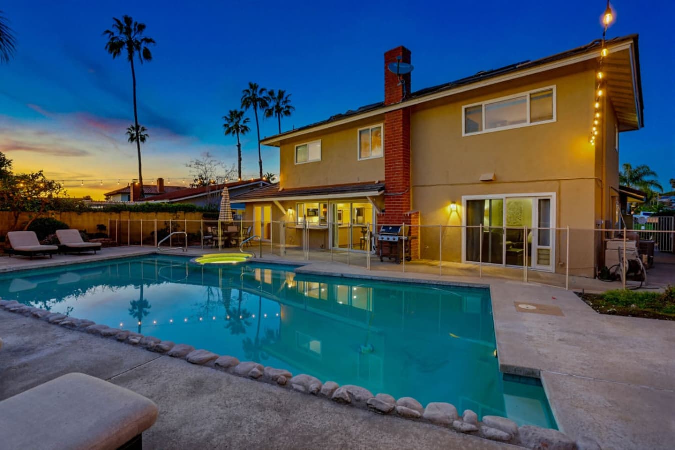 Poolside at dusk w/ soft lighting & calm water for peaceful evenings outside