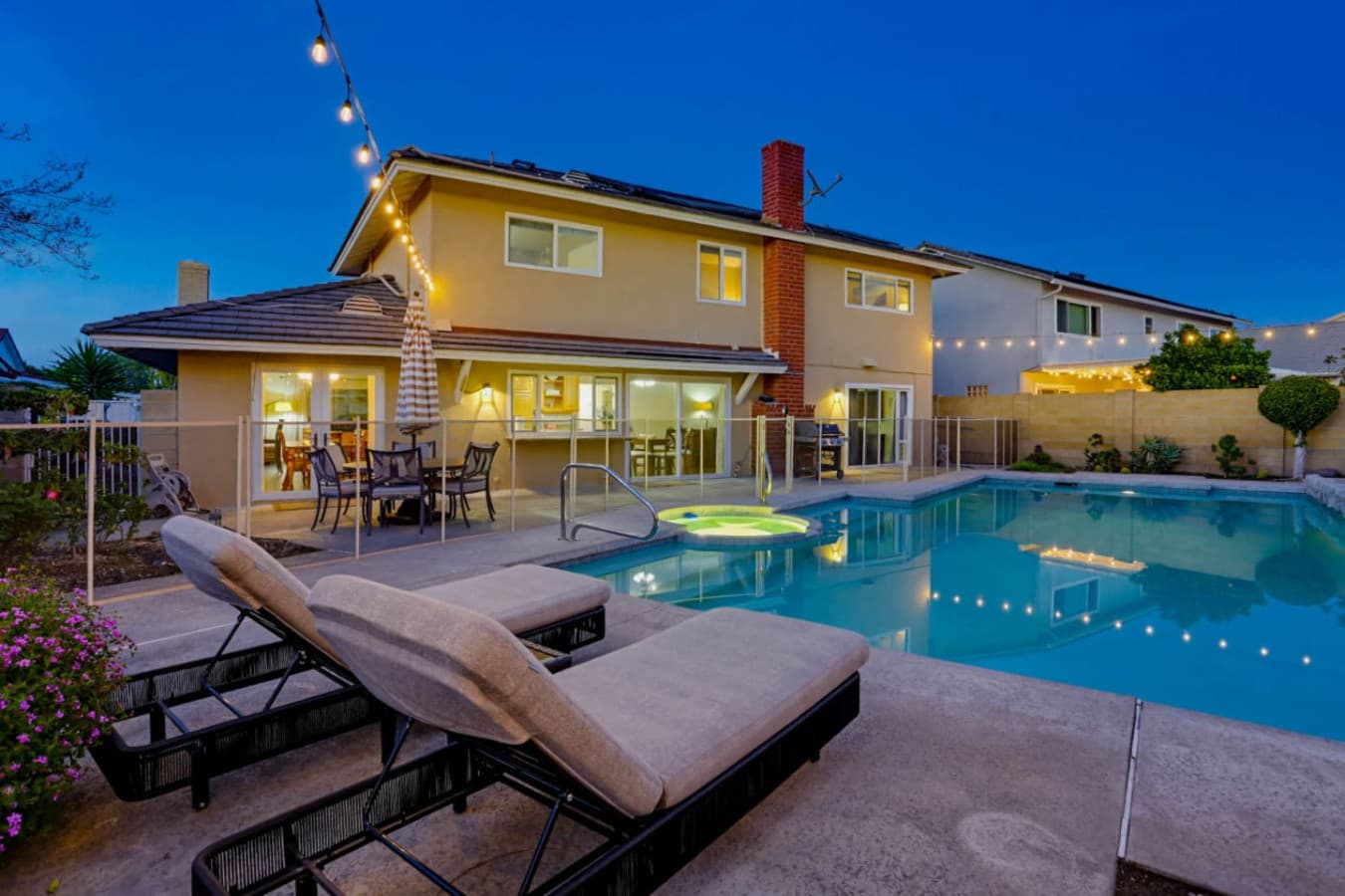 Evening backyard w/ lit pool & seating area, ideal for unwinding after sunset