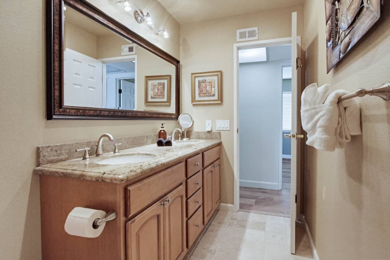 Bathroom vanity w/ wide counter, sink & mirror in a bright, clean setting