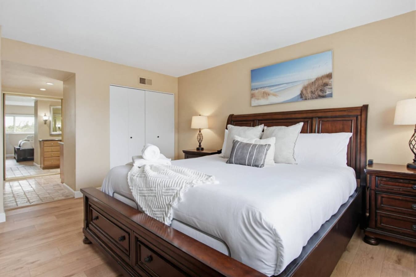 Bedroom w/ carved wood bed frame, matching nightstands & coastal art for restful nights.