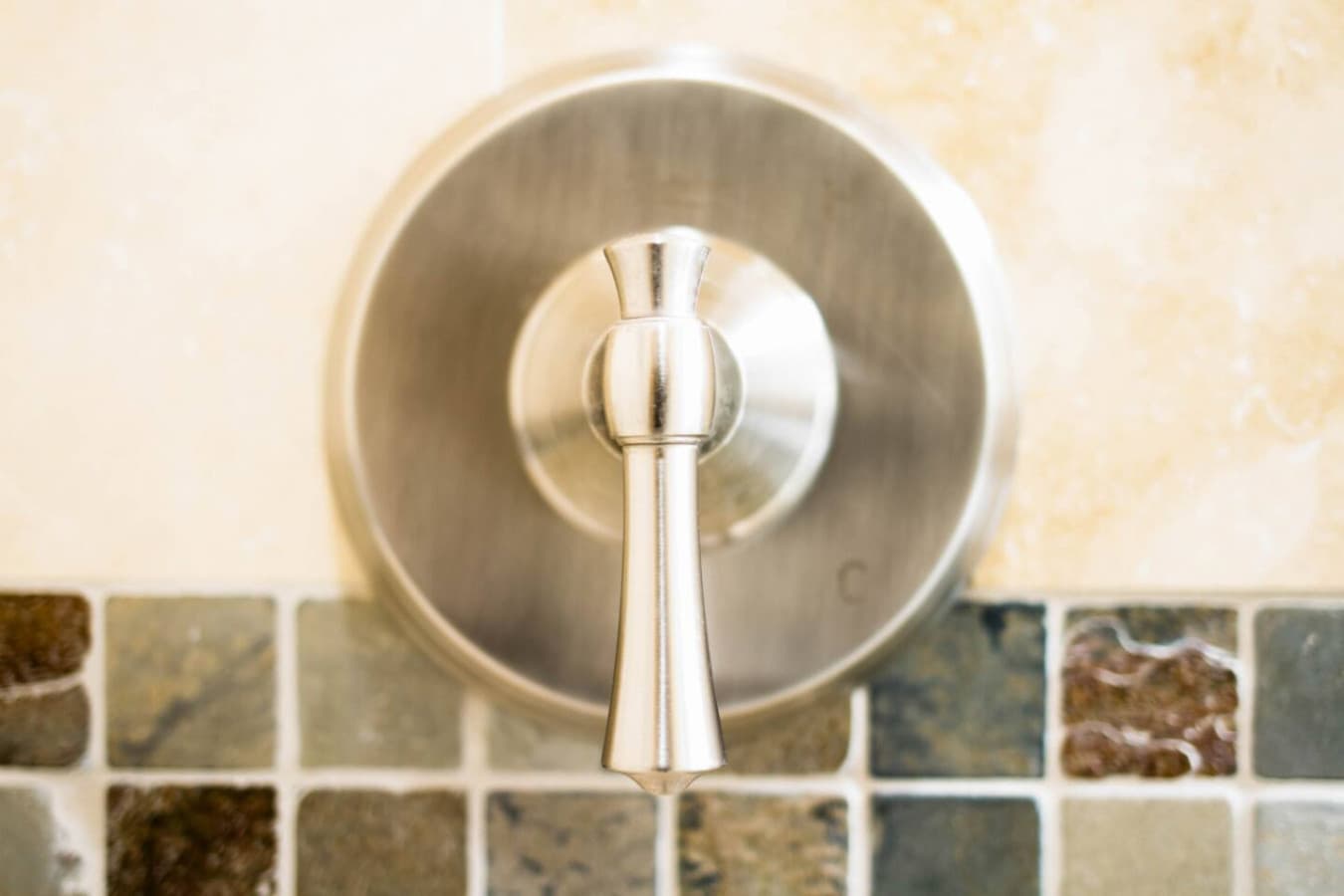 Shower valve & tile detail in a bathroom finished w/ natural stone accents.