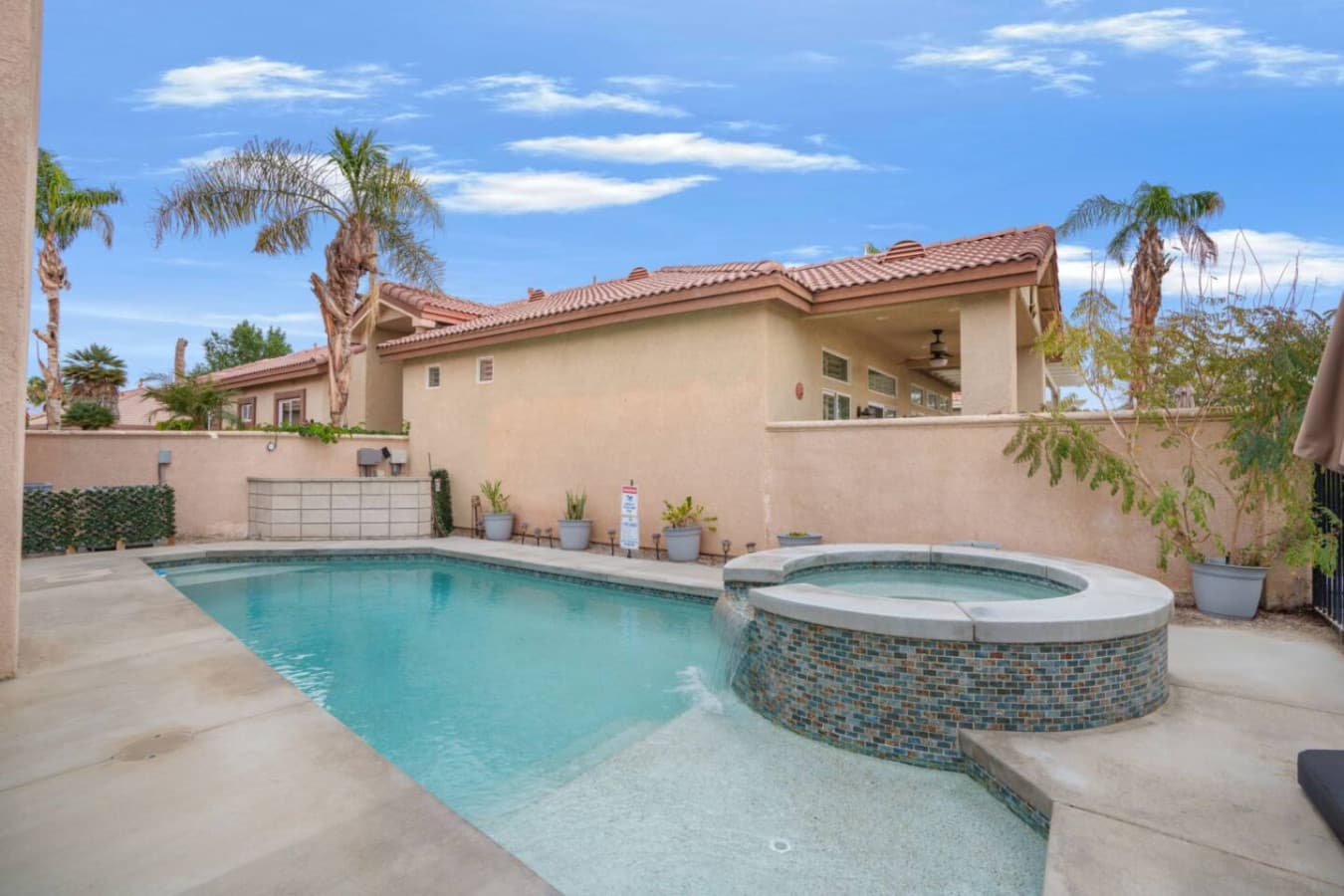 Private backyard pool w/ lounge seating and tall palms creating a relaxed desert escape.