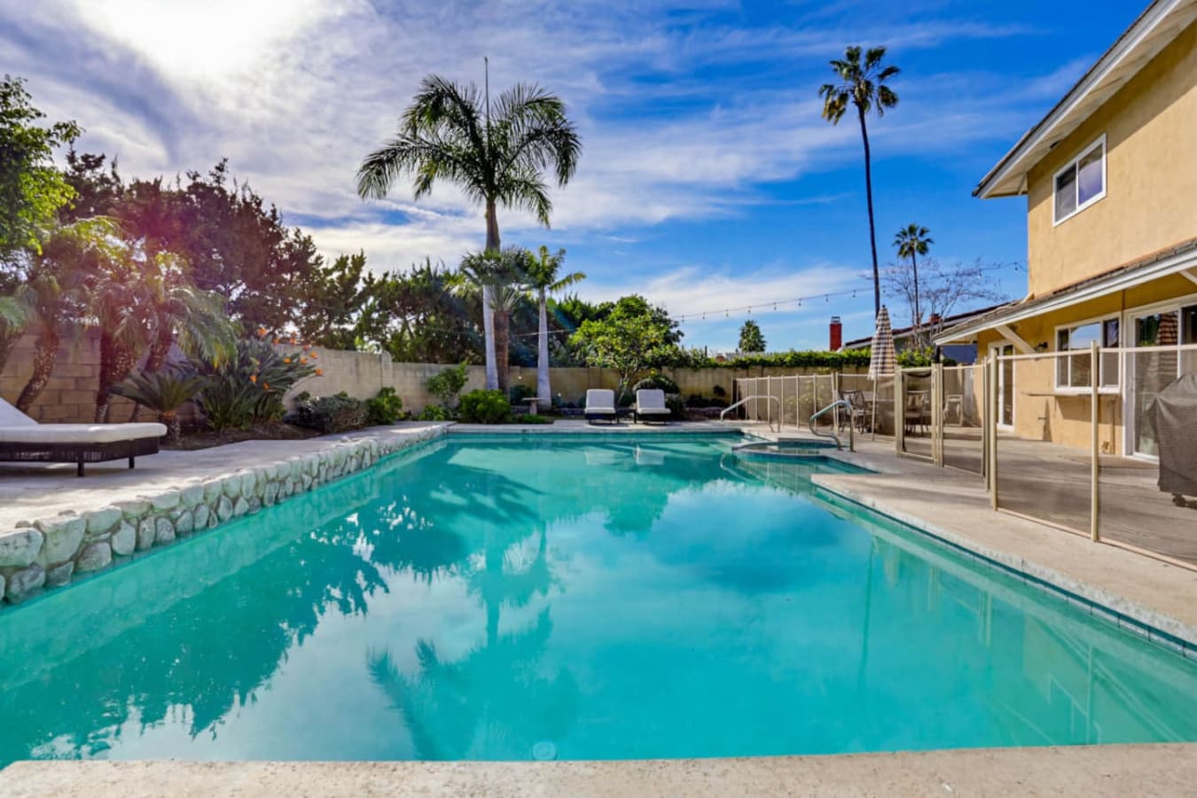 Inviting pool area w/ lounge chairs & palm trees, perfect for sunny afternoons