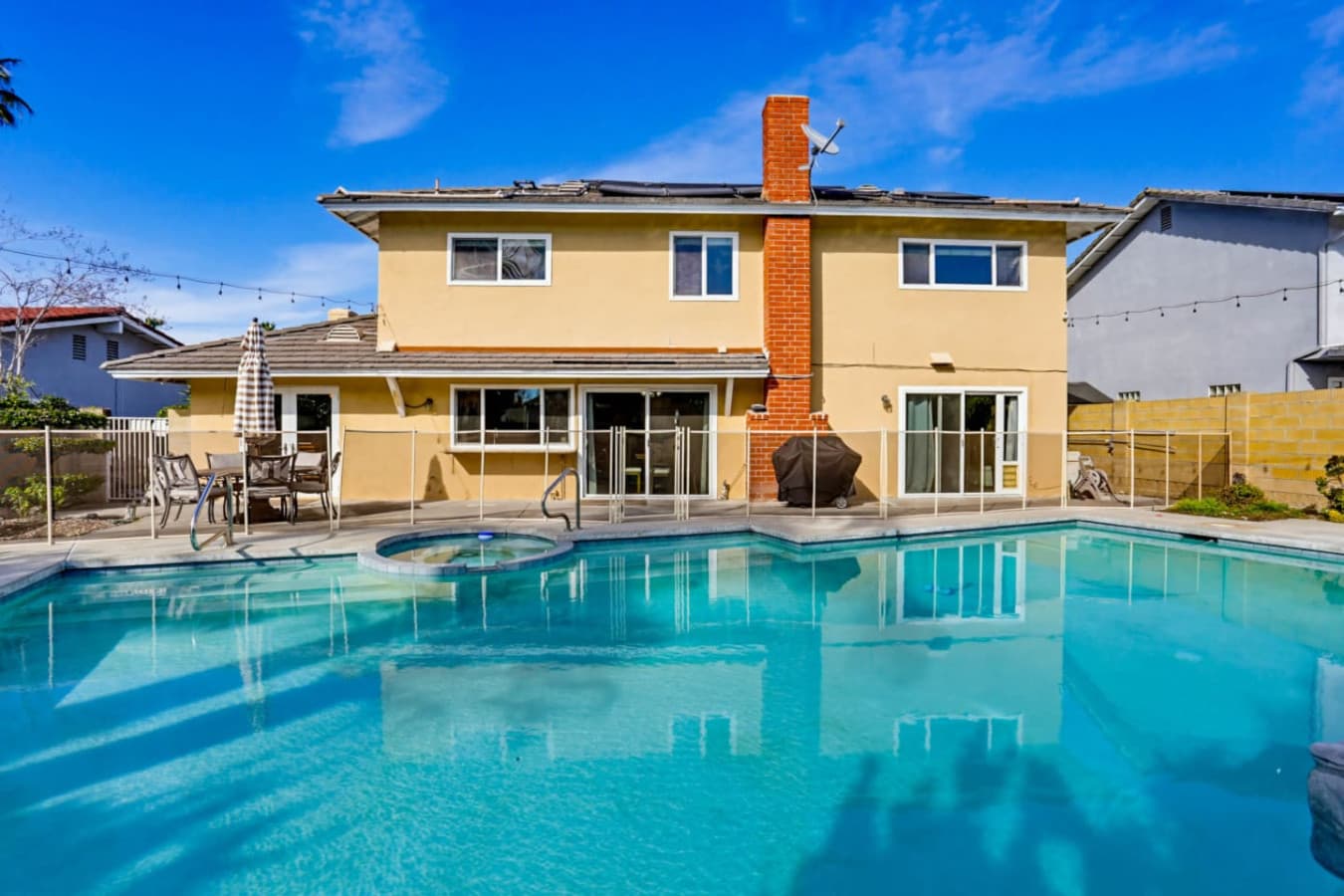 Backyard view of pool & home w/ wide patio space for gatherings