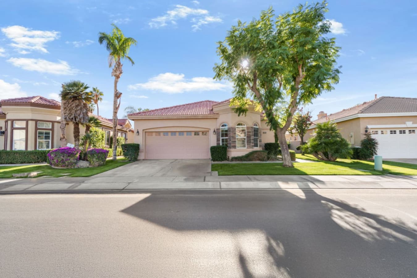 Welcoming front view w/ palm trees, driveway parking, and a sunny neighborhood feel.