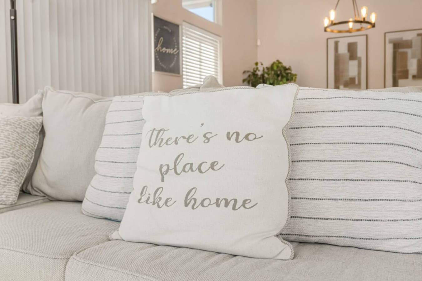 Cozy sofa pillows w/ an inviting message, perfect for settling in and feeling at home.