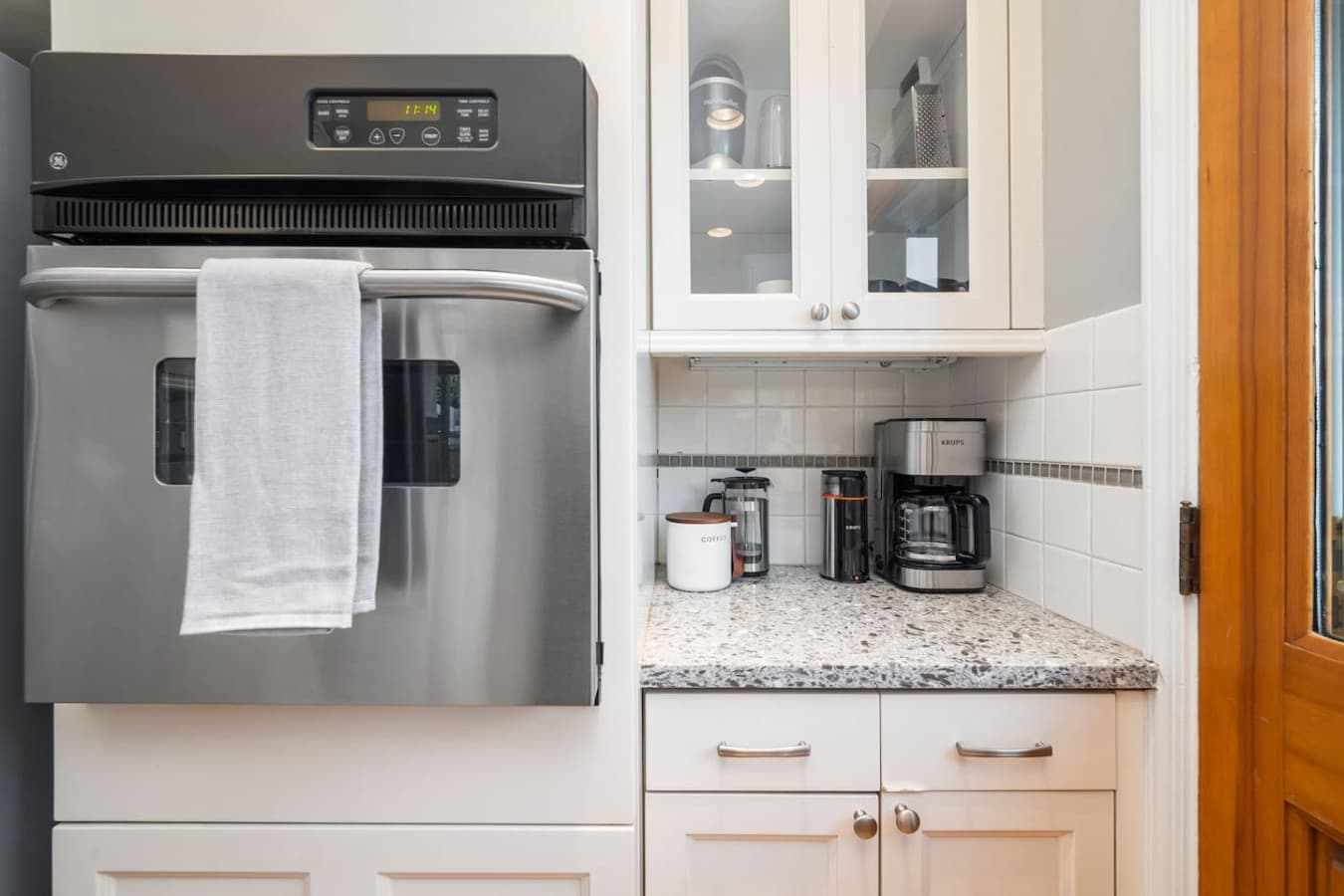 Built-in GE oven with a digital panel and stainless steel finish. Krups coffee maker. Coffee grinder. French press. Nutribullet blender (stored in the upper cabinet).