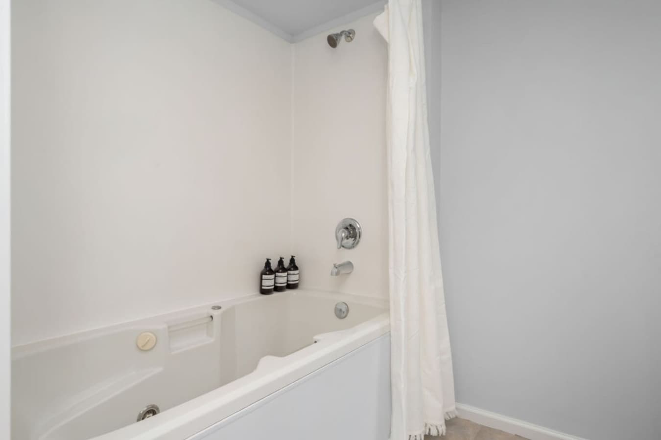 DOWNSTAIRS: The en-suite bathroom has a full bathtub and shower combo with shampoo, conditioner, and gel soap.