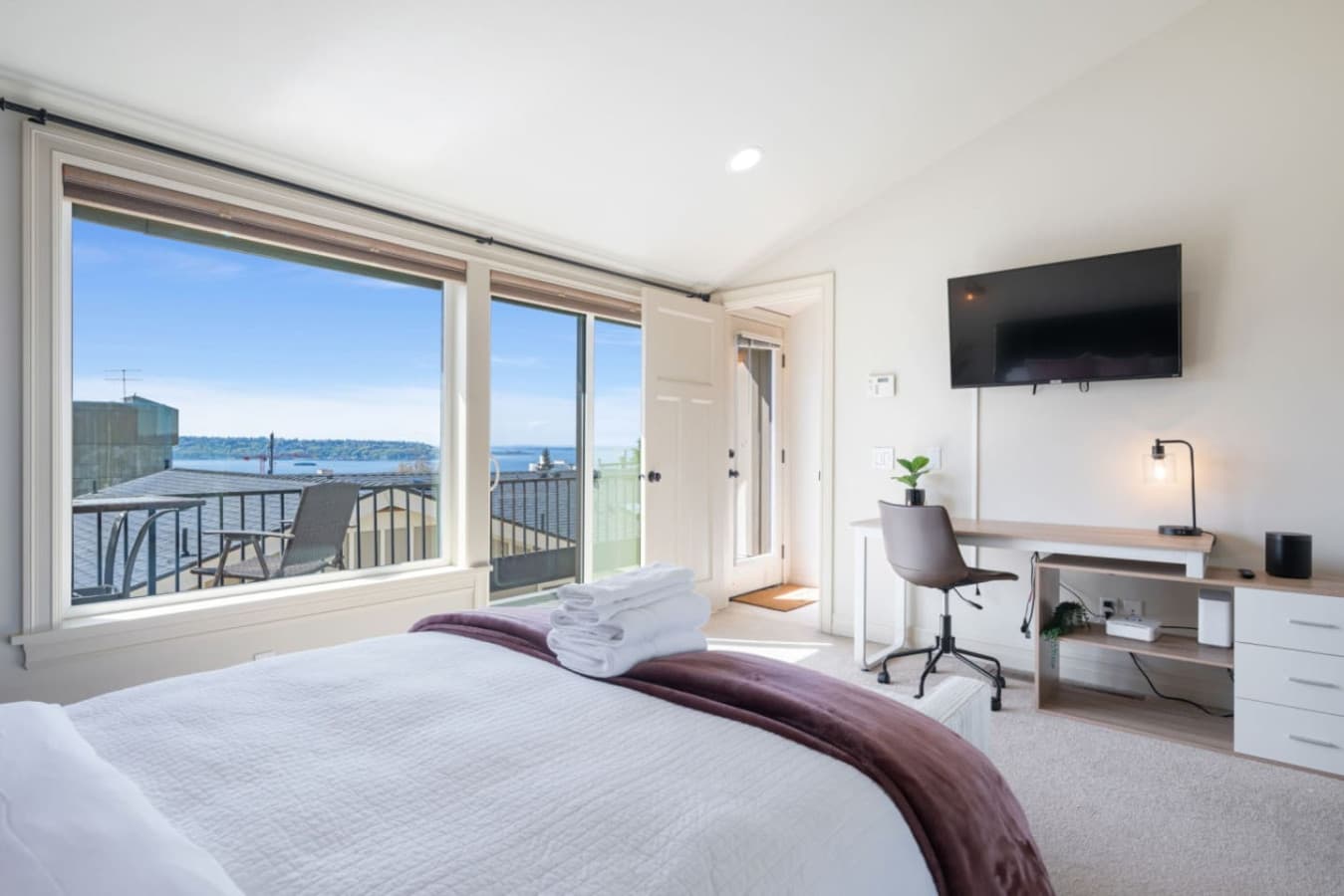 3rd FLOOR MASTER BEDROOM: Water view of Puget Sound, dedicated workspace, private balcony, queen-size bed, portable A/C, and en-suite bathroom.