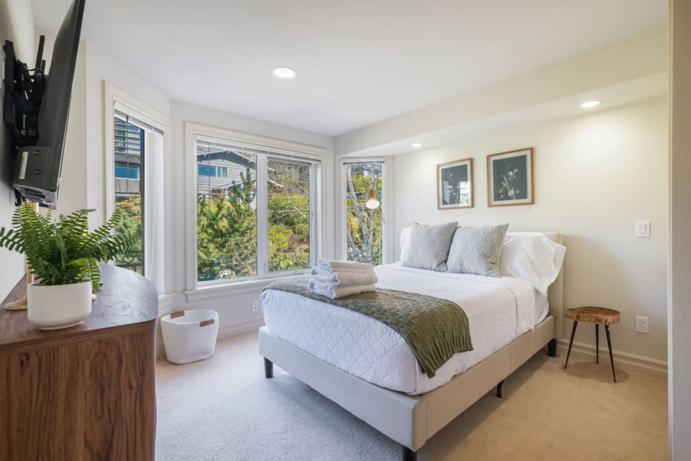 2nd Floor Bedroom 2: A bright and serene with large corner windows, a plush bed, elegant decor, and a Smart TV with major streaming services. A peaceful retreat for rest and relaxation.