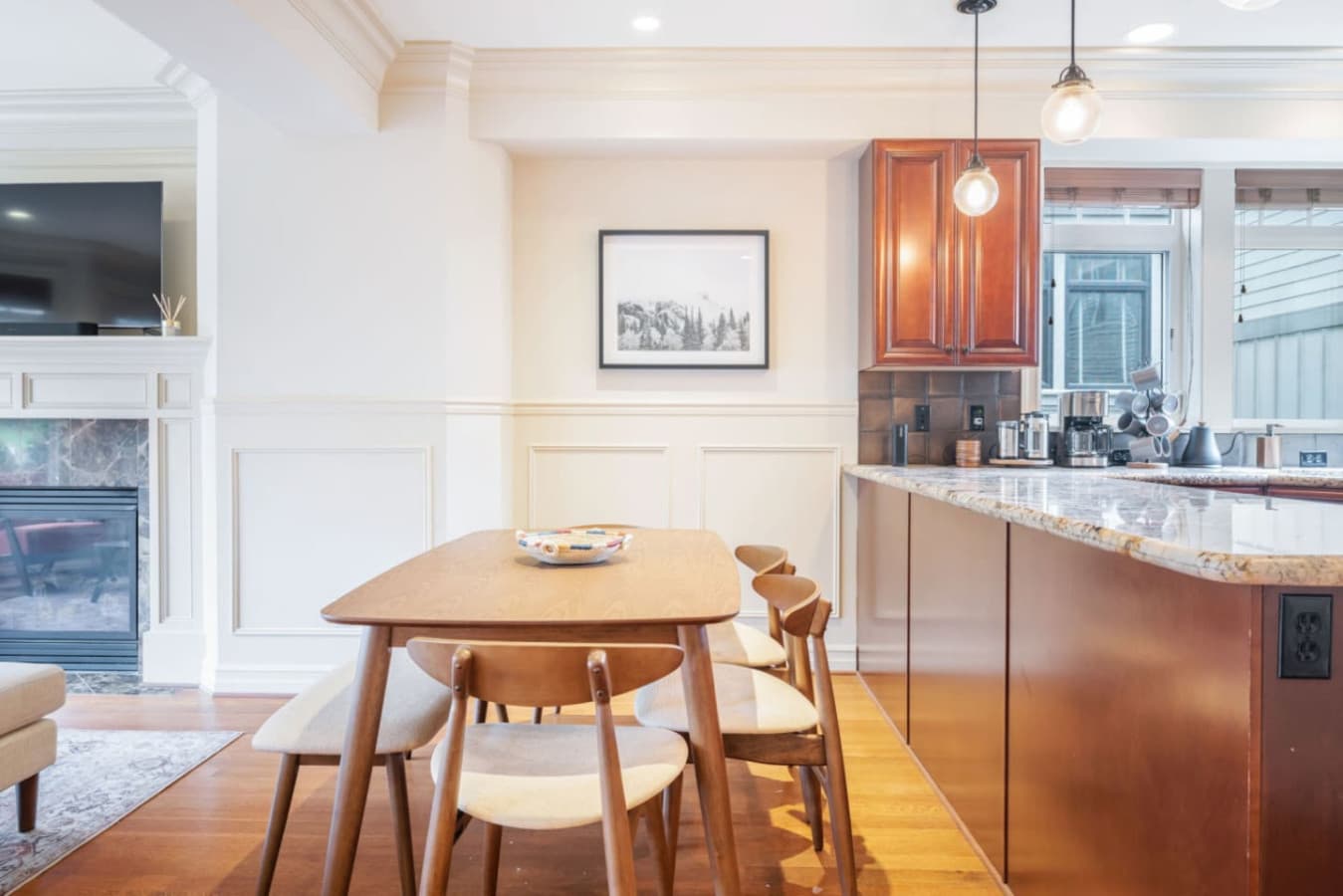 The dining table is a sleek wooden piece with a natural finish, surrounded by four matching chairs with beige upholstered seats and curved backrests