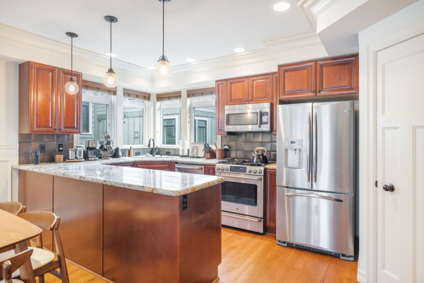 The kitchen, featuring dark wood cabinets and a stone countertop, is illuminated by two elegant pendant lights, adding charm to the space.