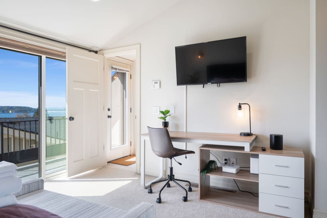 3rd FLOOR MASTER BEDROOM: Water view of Puget Sound, dedicated workspace, private balcony, queen-size bed, portable A/C, and en-suite bathroom.