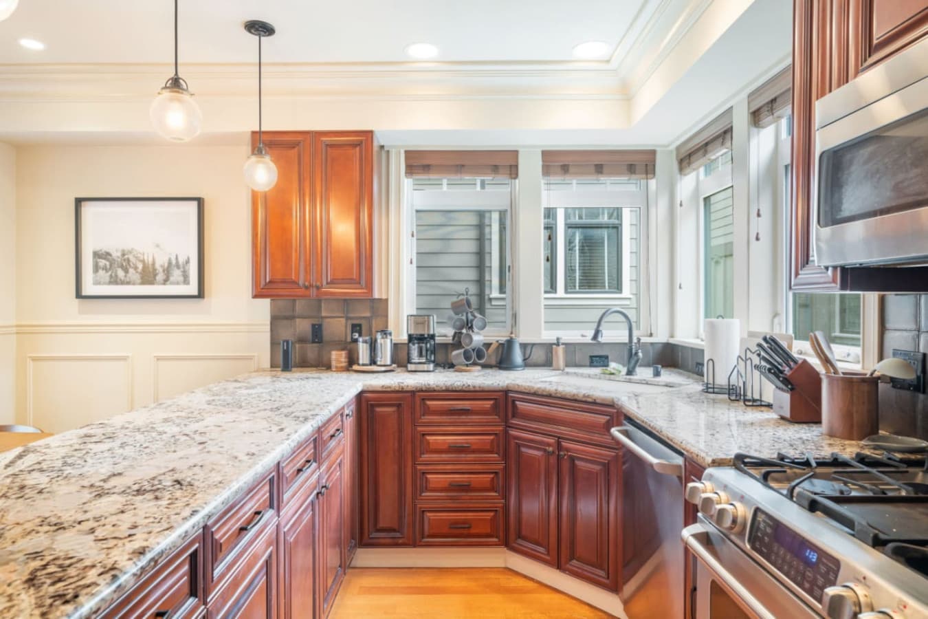 A coffee maker, electric kettle, and knife holder sit on the counter, with pendant lighting adding warmth.