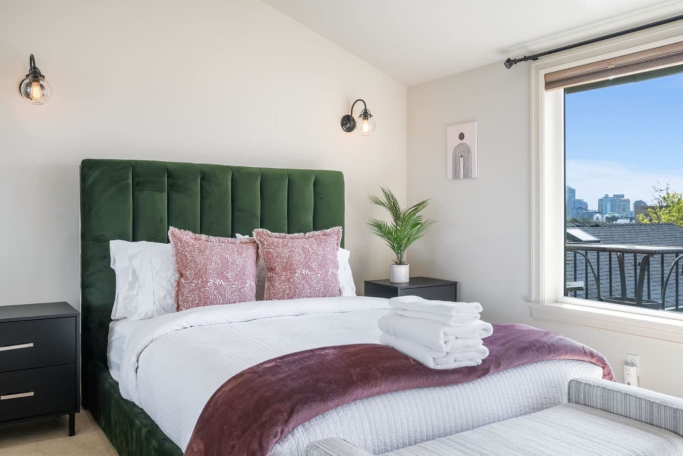 A cozy and elegant bedroom with a plush green velvet headboard, mirrored wall, and modern decor for a relaxing stay.