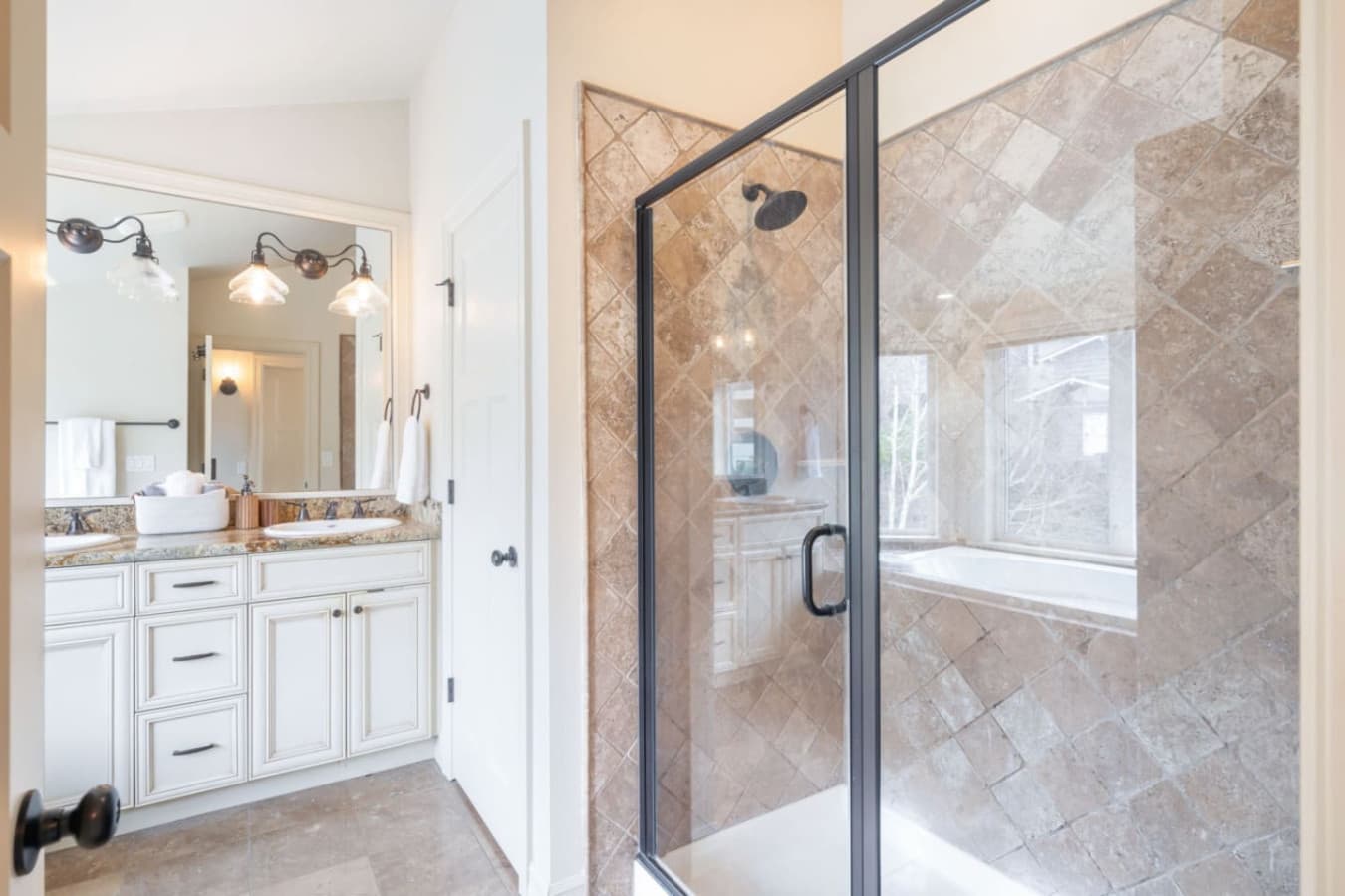 The en-suite bathroom features a soaking tub, spacious shower, double vanity, and elegant lighting. We also provide shampoo, shower gel, and conditioner.