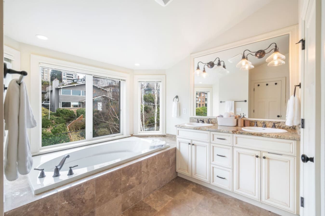 The en-suite bathroom features a soaking tub, spacious shower, double vanity, and elegant lighting. We also provide shampoo, shower gel, and conditioner.