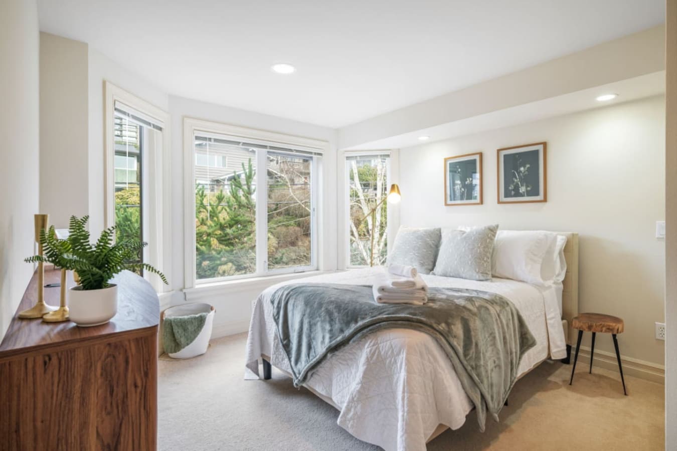 2nd FLOOR BEDROOM 2: This inviting and peaceful bedroom includes a full-size bed with soft linens, wooden bedside tables, a standing lamp, and a spacious closet for storage. Large windows bring in plenty of natural light, while blinds ensure privacy