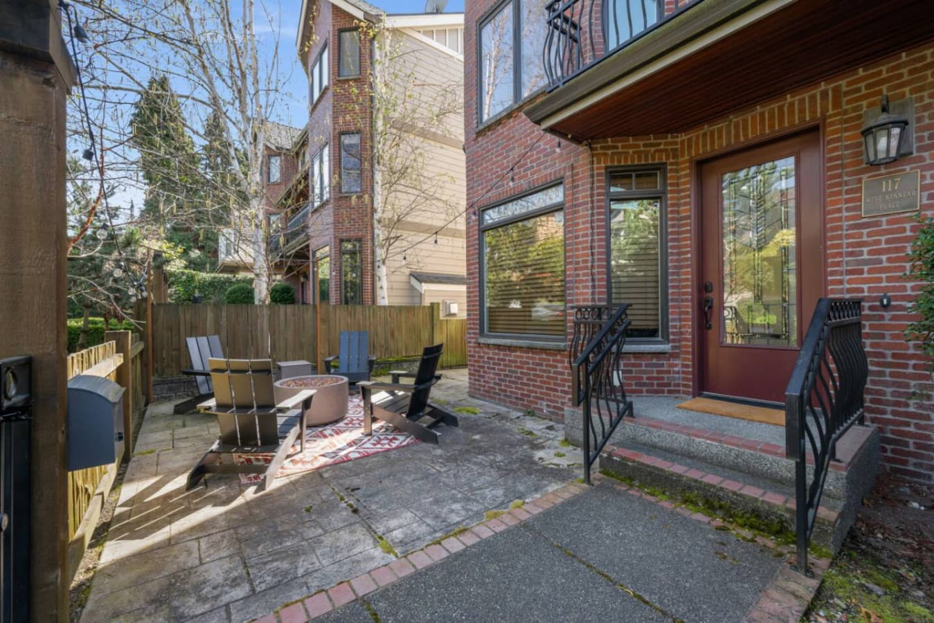 A short staircase with elegant black wrought iron railings leads to the entrance. The concrete steps with brick accents blend seamlessly with the classic brick façade, adding charm and character. The sturdy railings provide both style and safety, mak