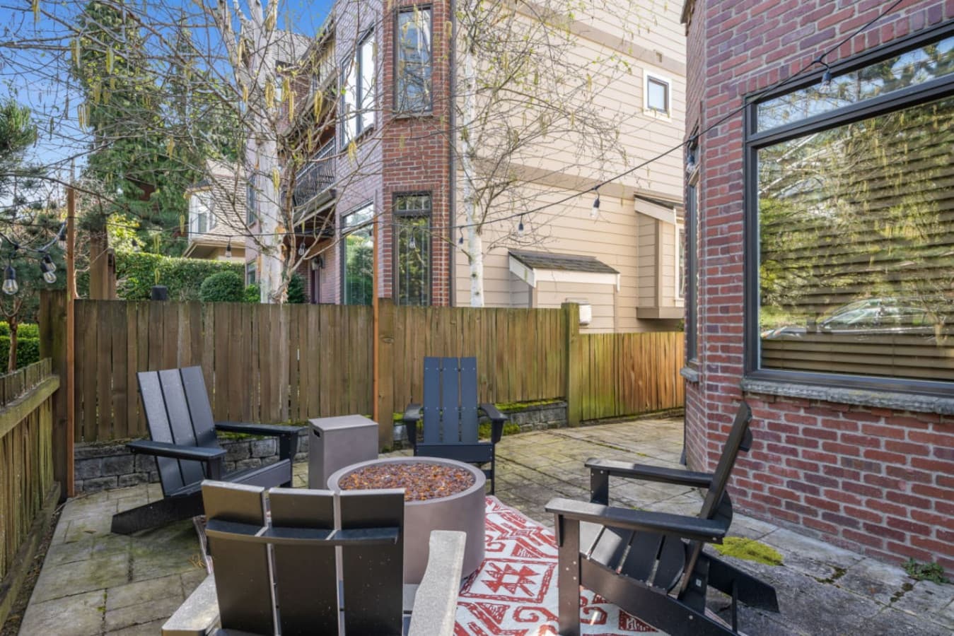 Four black Adirondack chairs are thoughtfully arranged around a circular fire pit, ideal for chilly evenings.