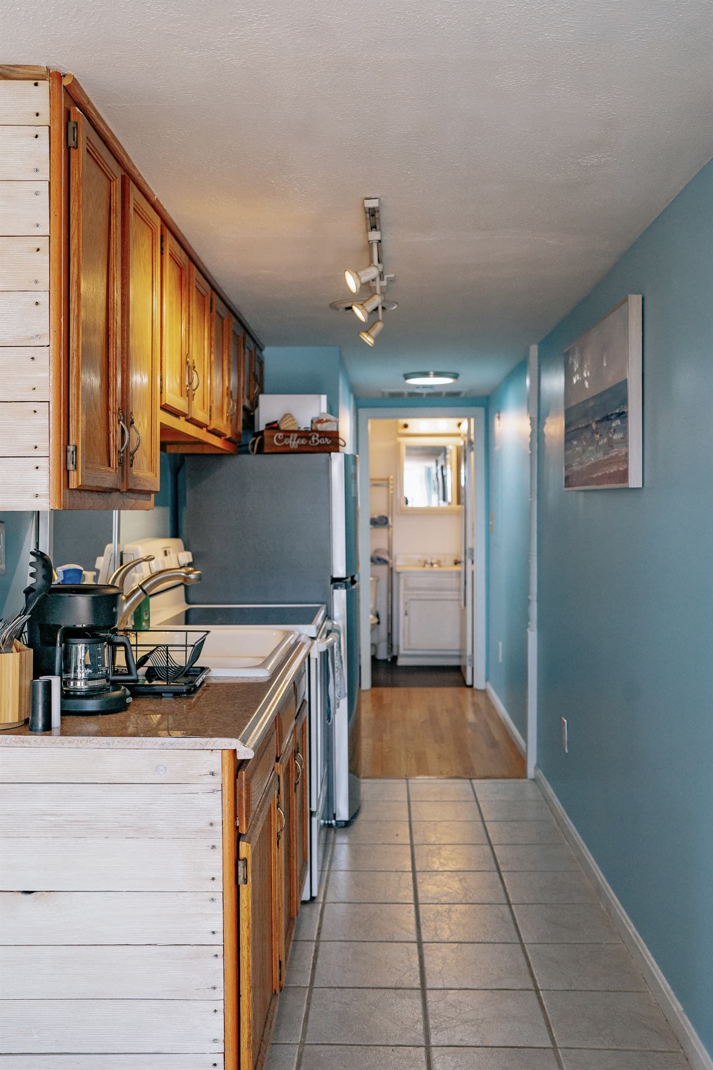 this picture was taken in the living room, showing the kitchen and entrance to the bathroom. The entrance to the master beroom is also in this hallway. The kitchen is fully stocked with essentials including coffee maker, forks & knives, cooking oil, etc