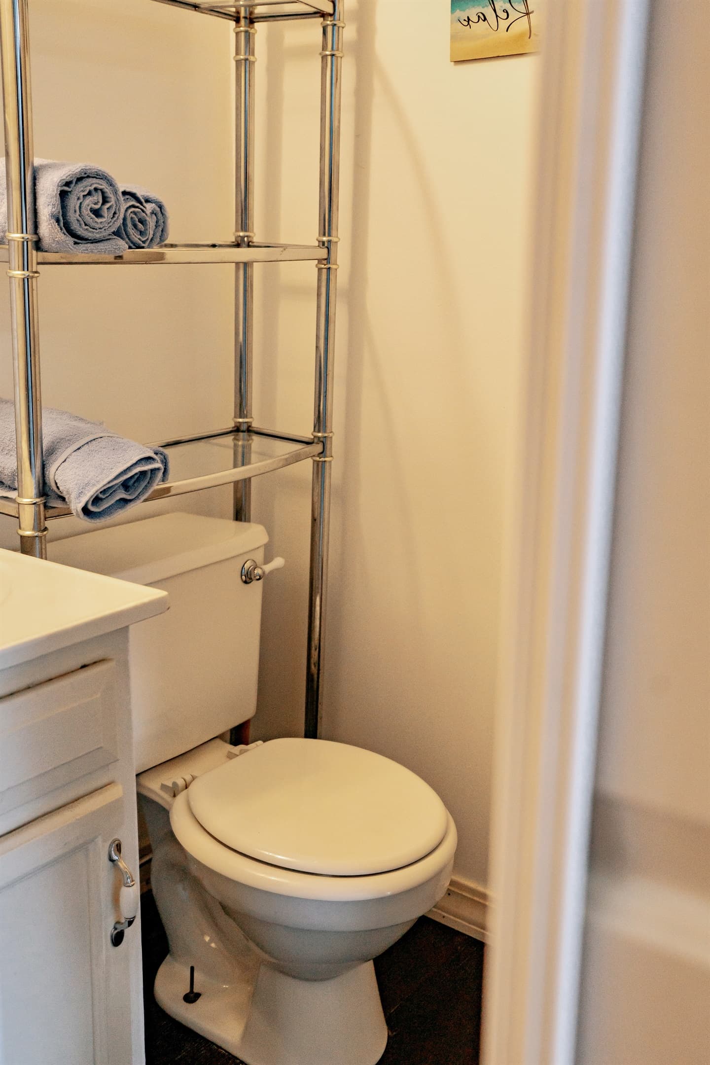 another shot of the bathroom including the toilet, above toilet shelf