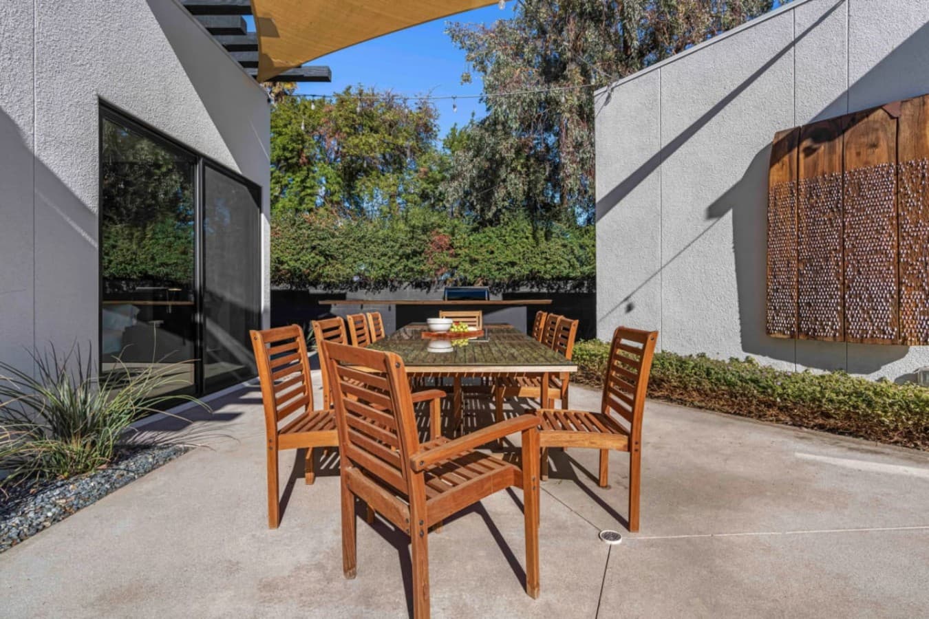 Private outdoor dining patio w/ wood table, desert walls, and string lights for easy meals outside.