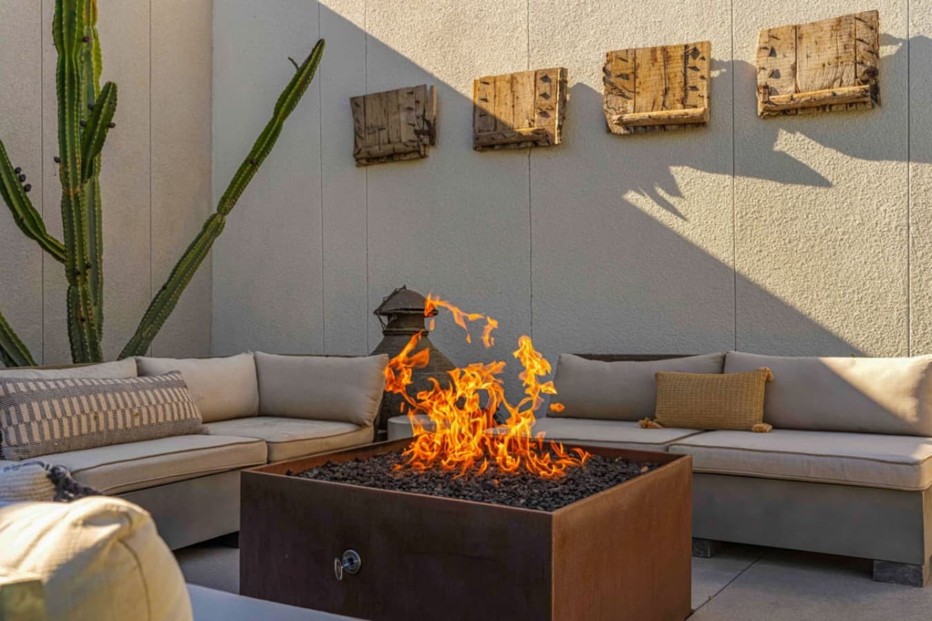 Cozy fire pit lounge w/ built-in seating, warm flames, and desert textures perfect for evening chats.