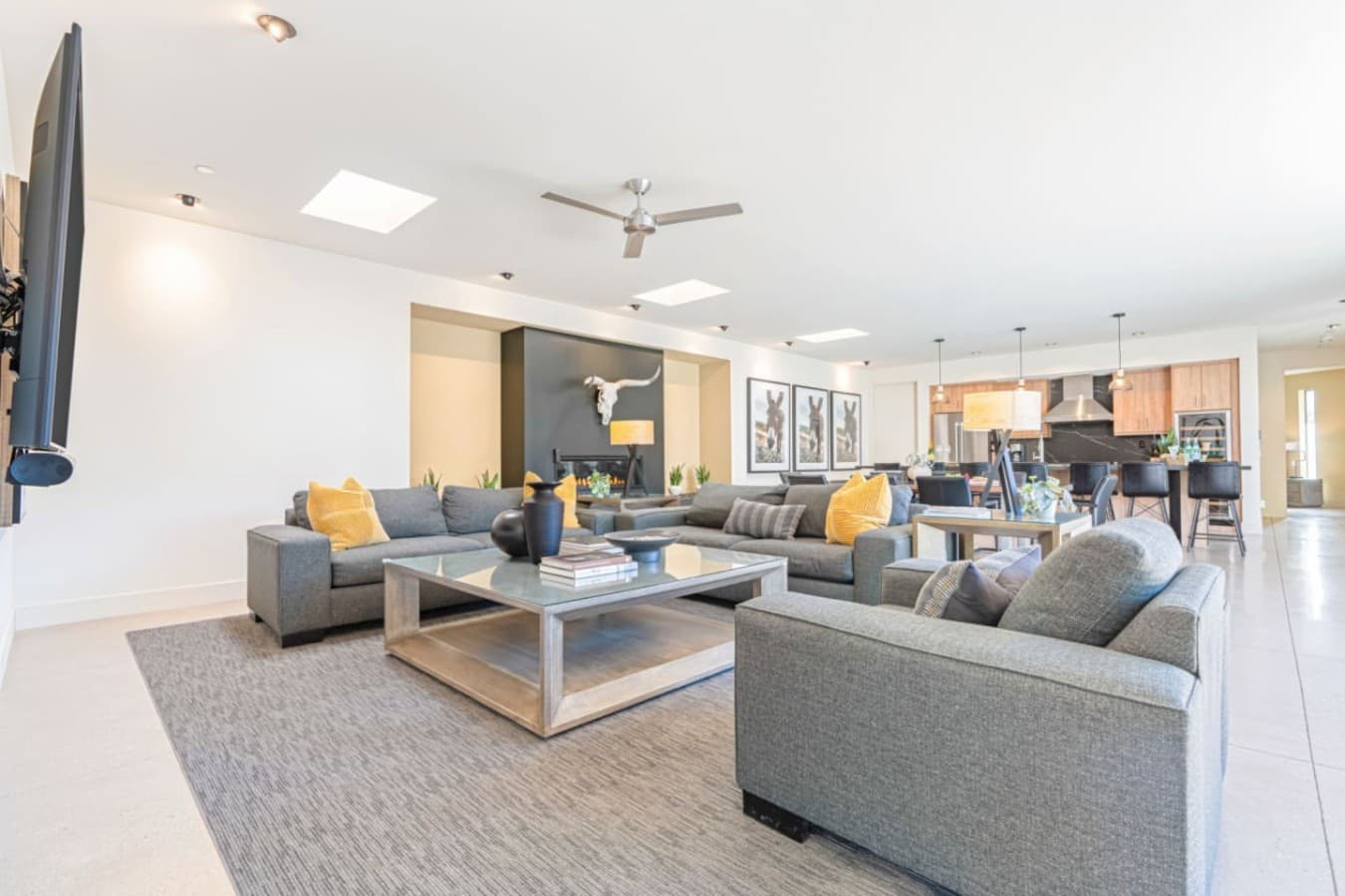 Airy living room w/ modern sofas, ceiling fan, and open sightlines across the main space.