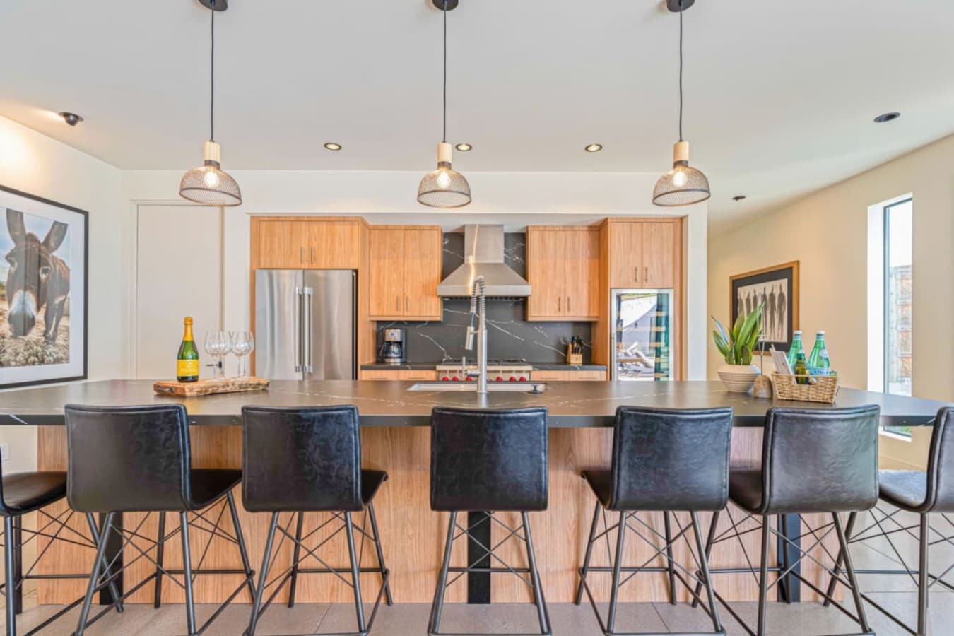 Bar-style island seating w/ sleek stools, warm wood accents, and a welcoming spot to linger.