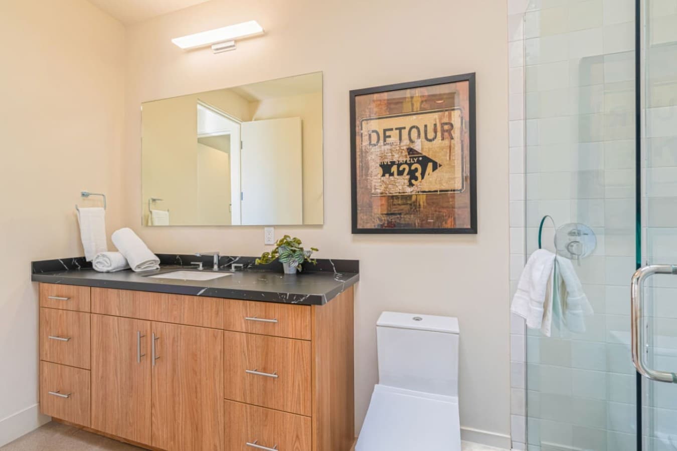 Clean-lined bath w/ wood vanity, walk-in shower, and simple decor for a fresh, uncluttered feel.